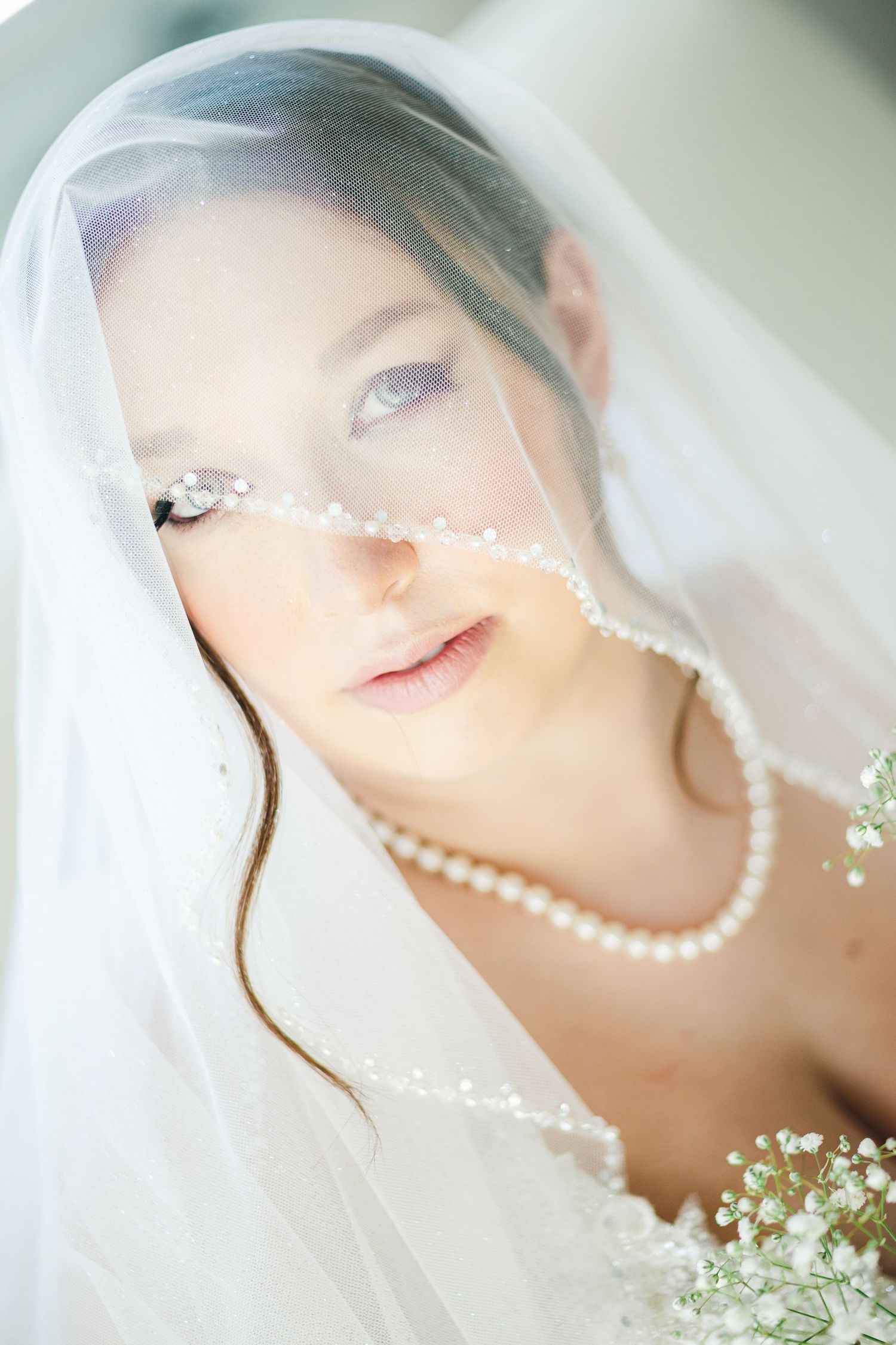 Elegant bridal portrait featuring pearl necklace and delicate veil details.