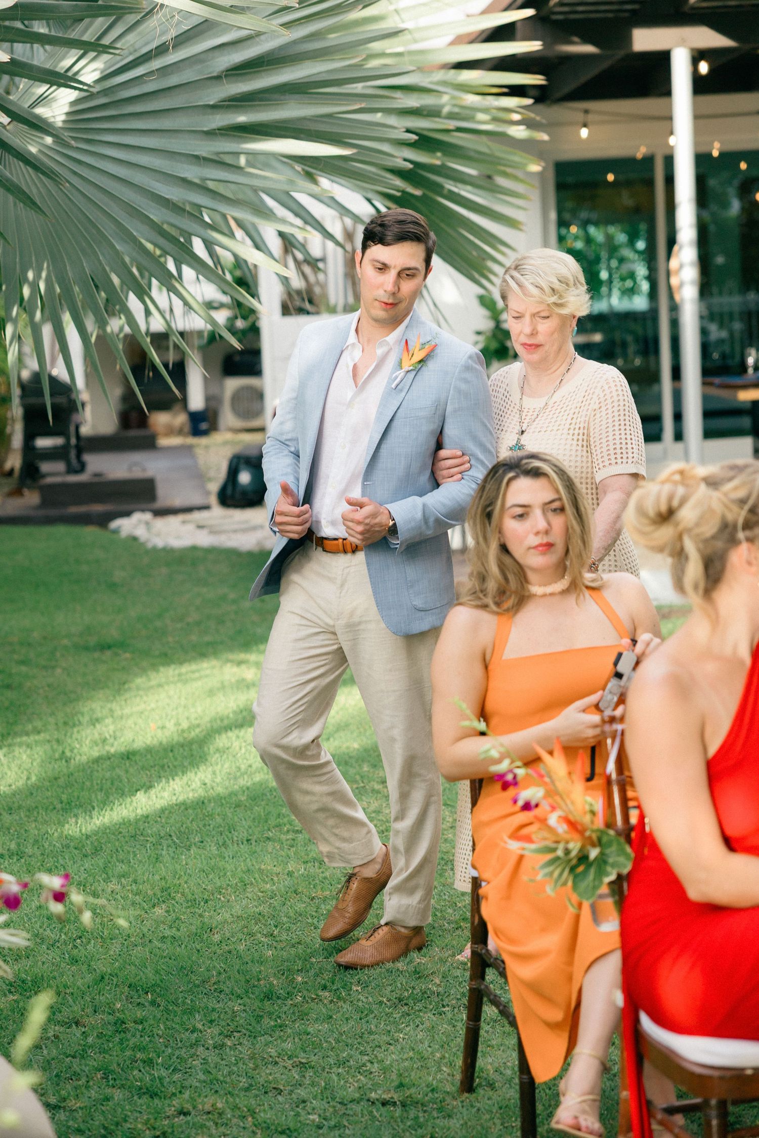 Tropical wedding venue with palm trees and guests in colorful attire.
