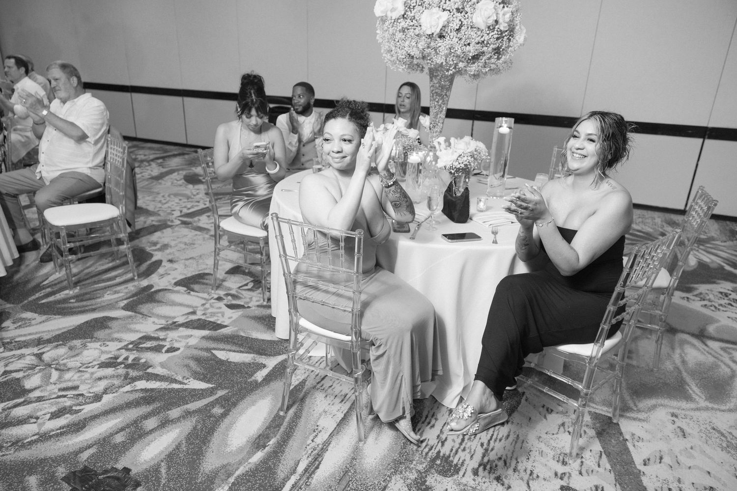 Black and white photo captures couples dancing at a formal wedding reception.