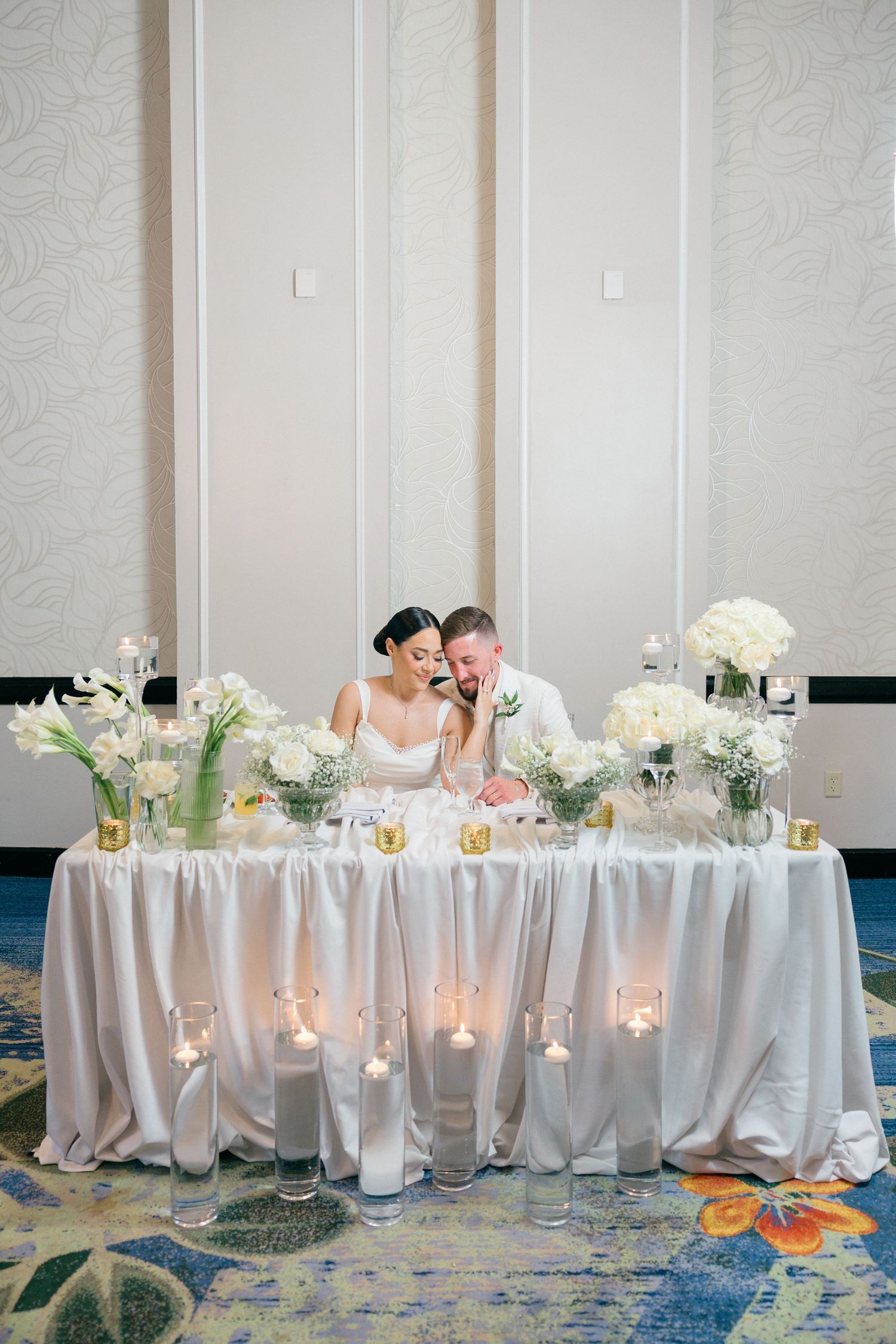 Elegant wedding head table decorated with white flowers and candles.