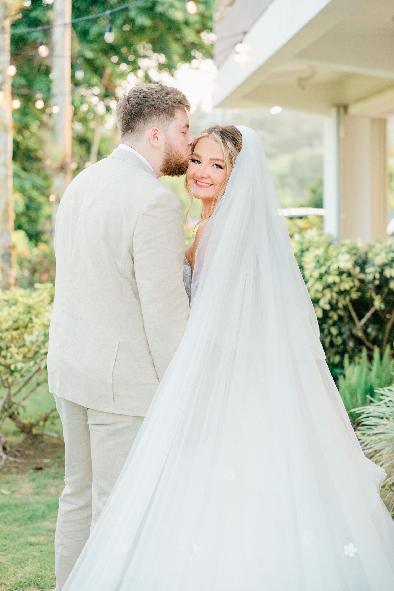 Romantic wedding portraits in a garden setting with flowing white dress and light colored suit.