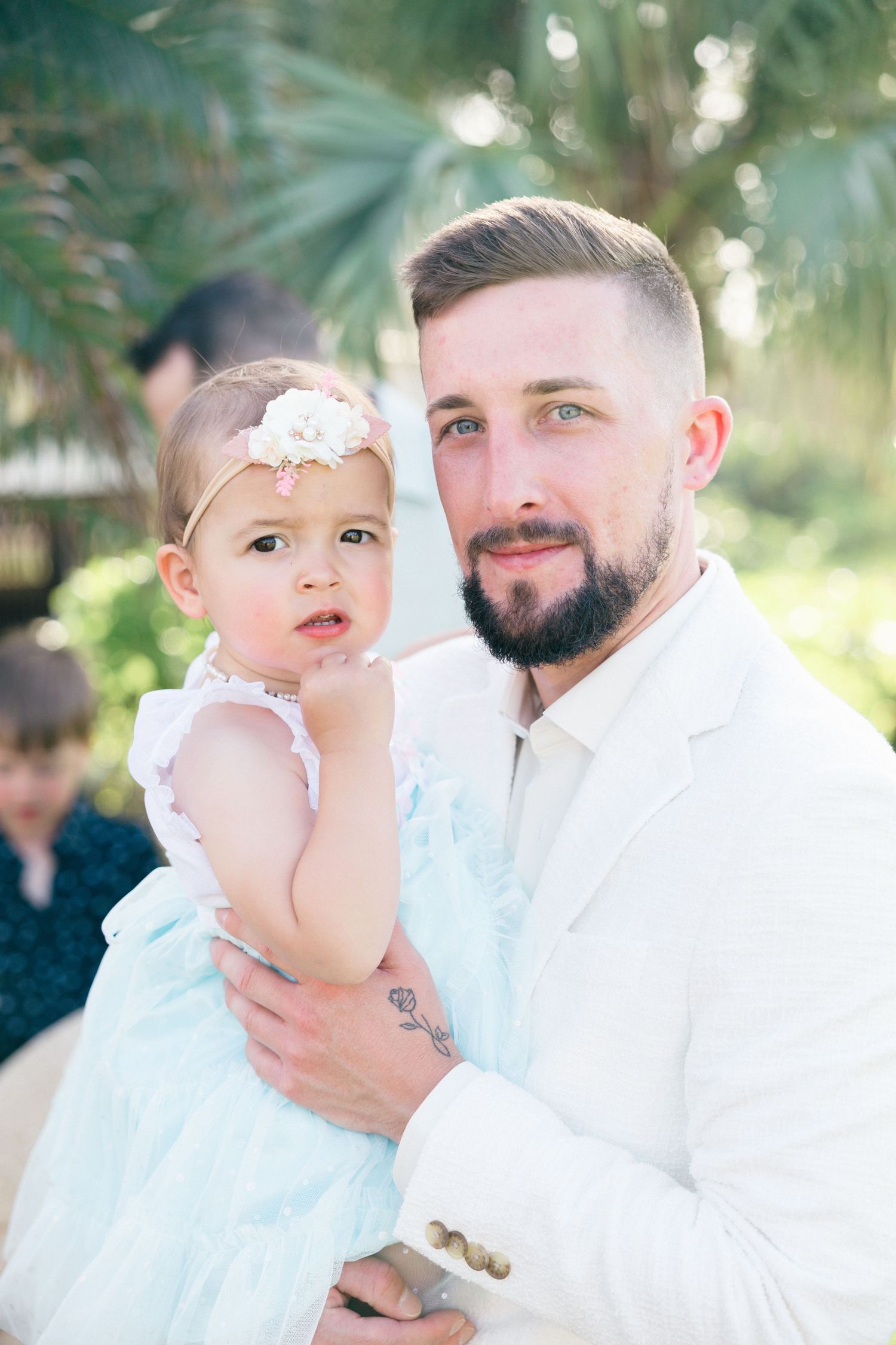 A tender moment captured in white attire against a soft tropical background.