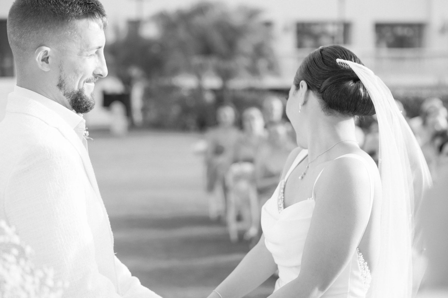 Black and white photograph of wedding ceremony participants interacting outdoors.
