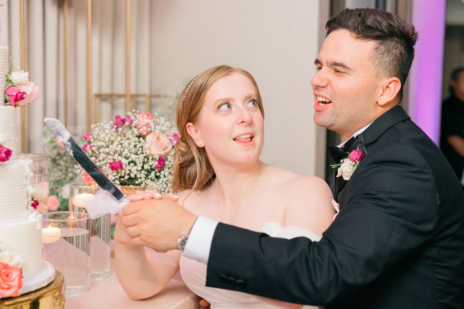 Couple shares an intimate dance at their wedding reception with pink floral decor and purple uplighting.