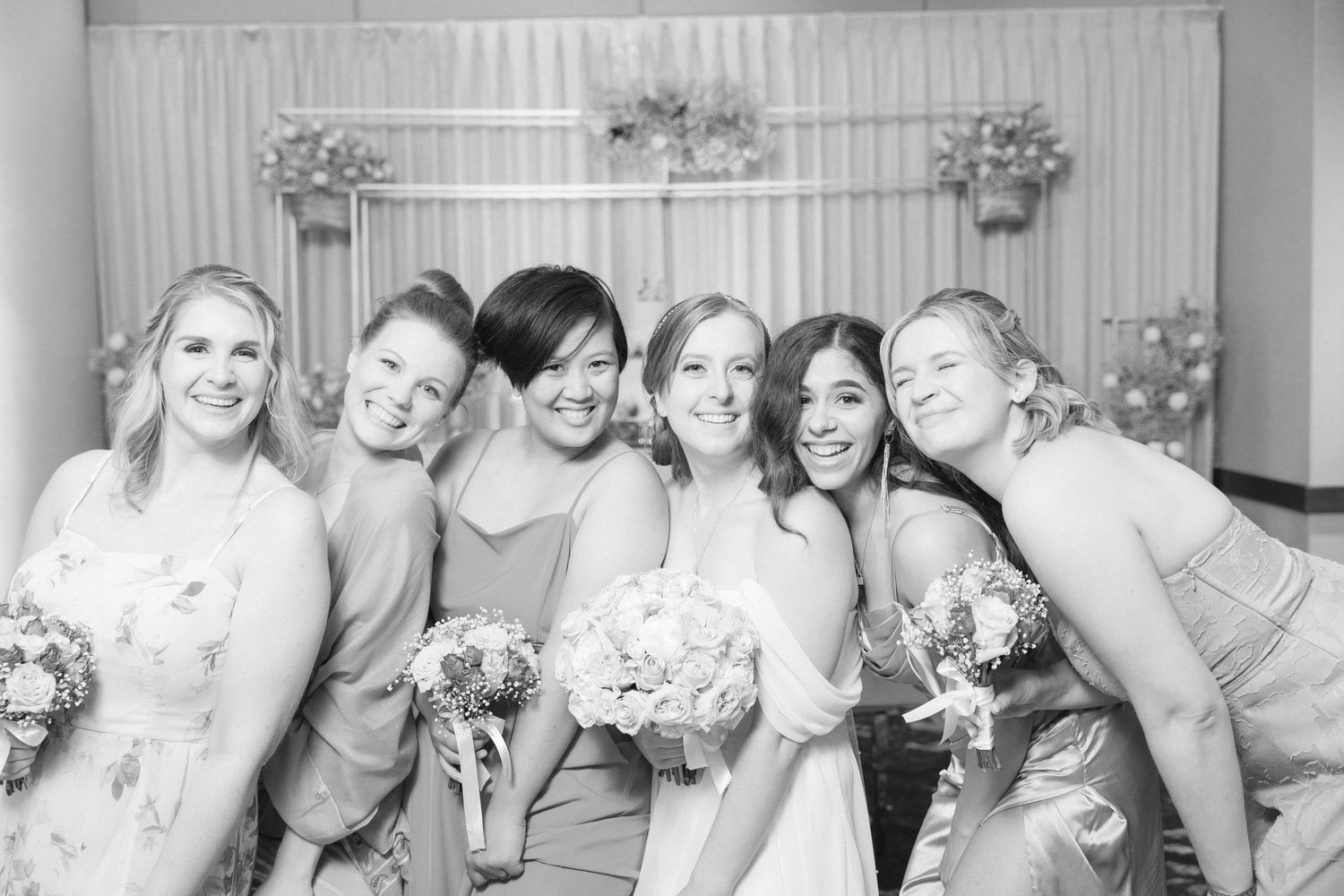 Black and white candid photo of bridesmaids sharing a joyful moment.