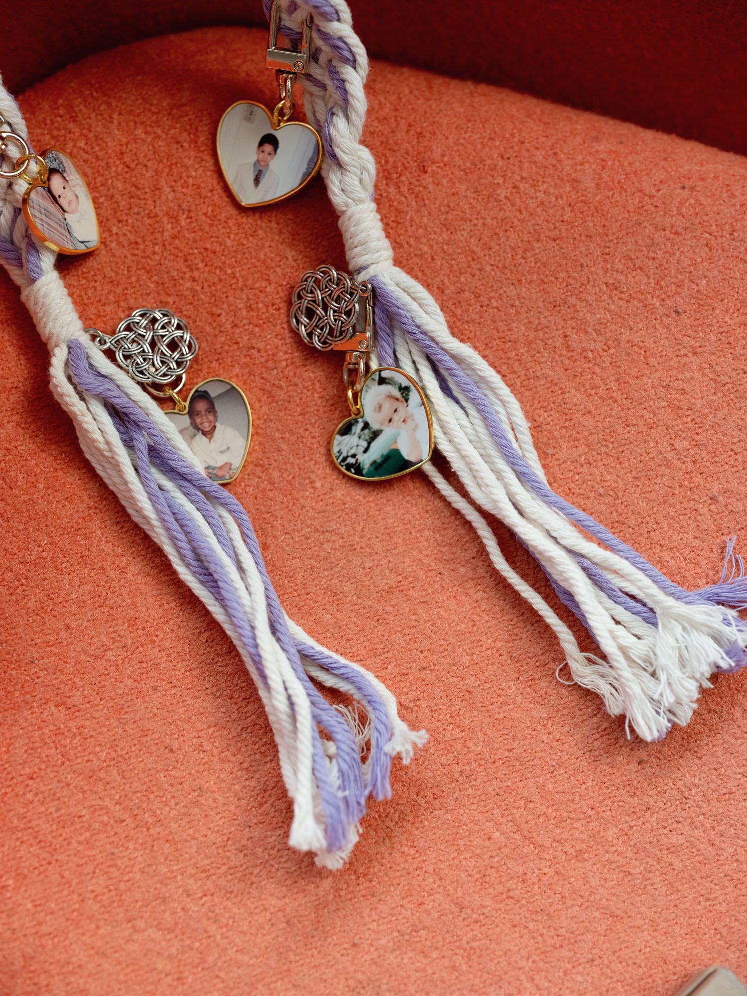 Decorative tassels in purple and white hanging against a coral colored wall.