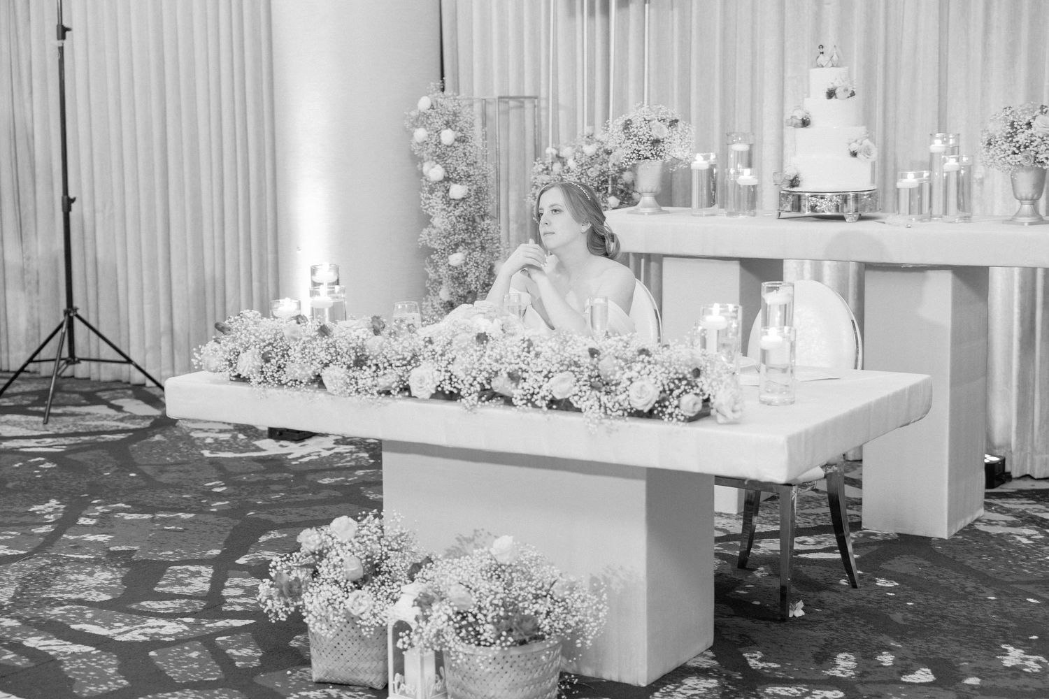 Wedding reception dessert table decorated with white floral arrangements and a tiered cake.