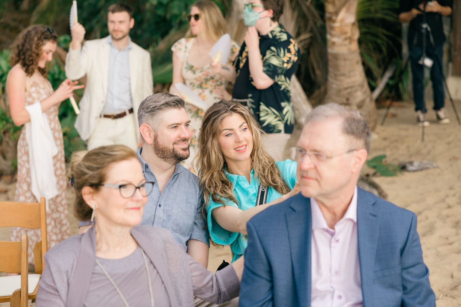 Wedding guests seated in wooden chairs at outdoor ceremony venue.