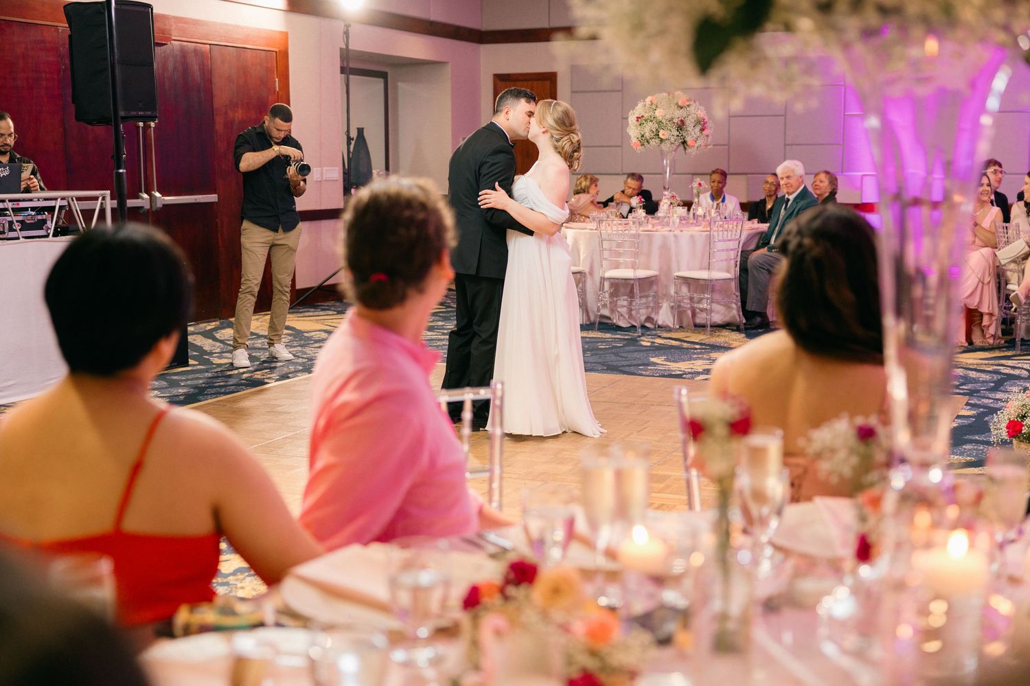 Wedding reception tables decorated with pink florals and candlelight create romantic ambiance.