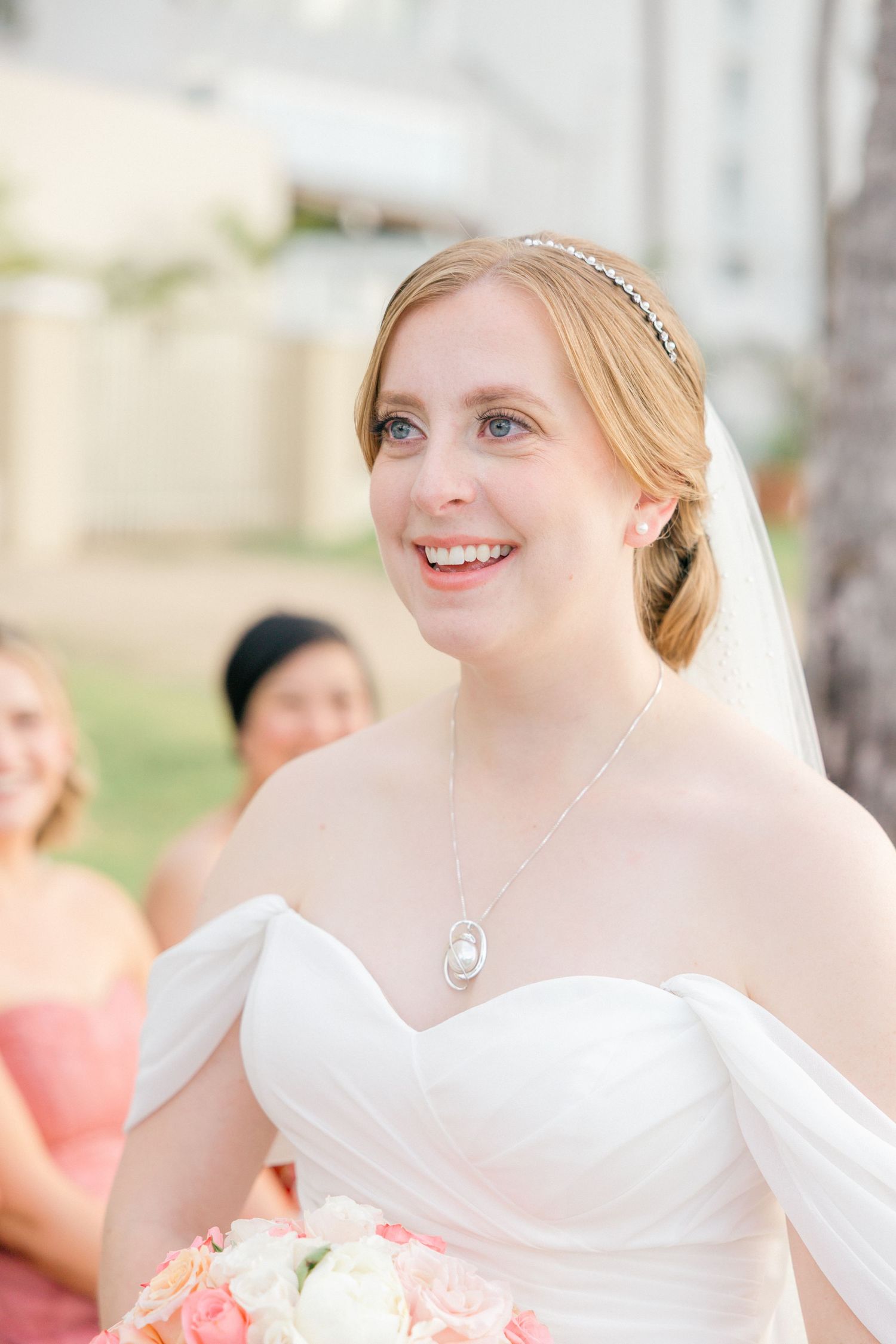 Elegant bridal portrait showcasing white dress and veil against outdoor setting.