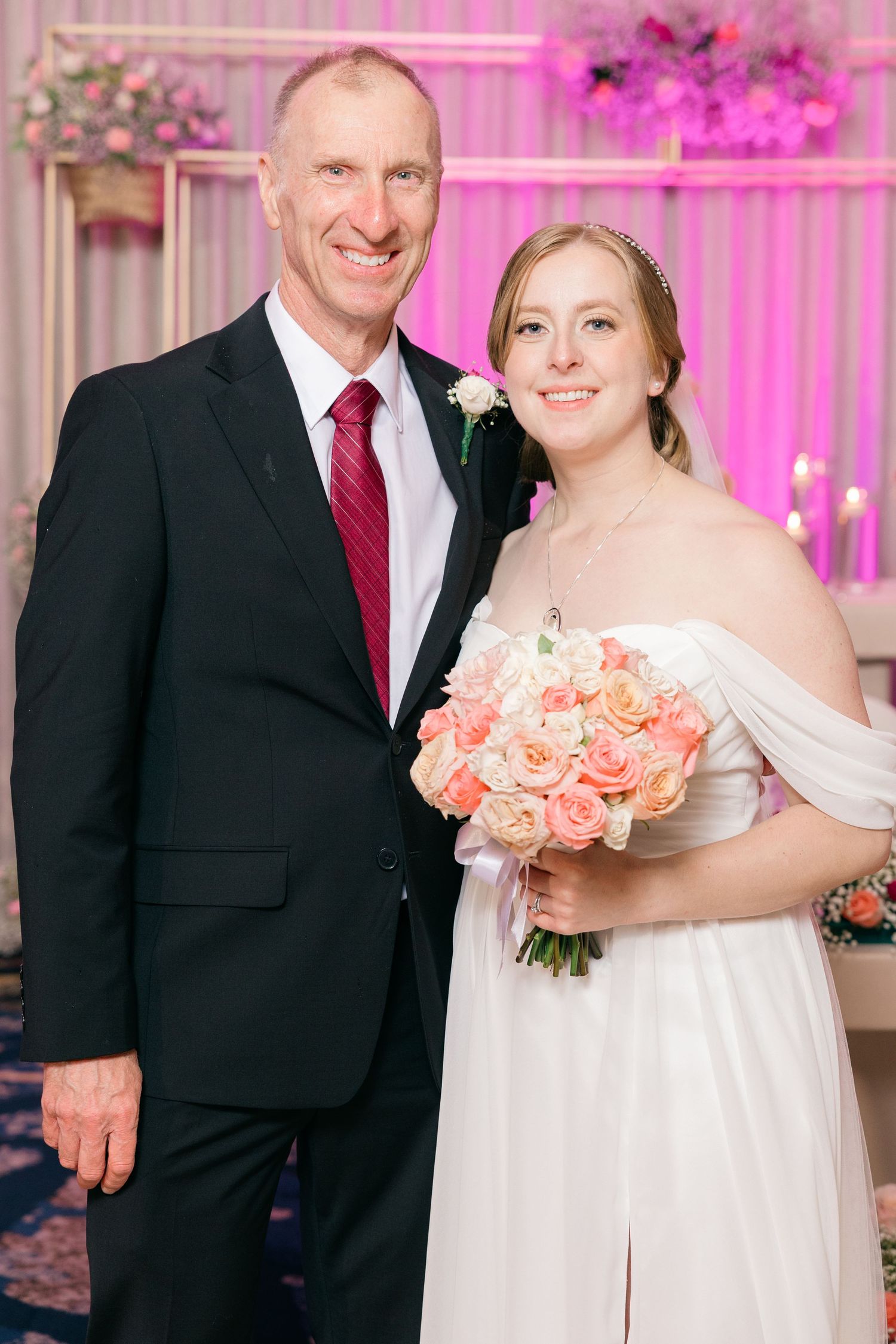 A wedding portrait with pink floral accents and soft lighting.