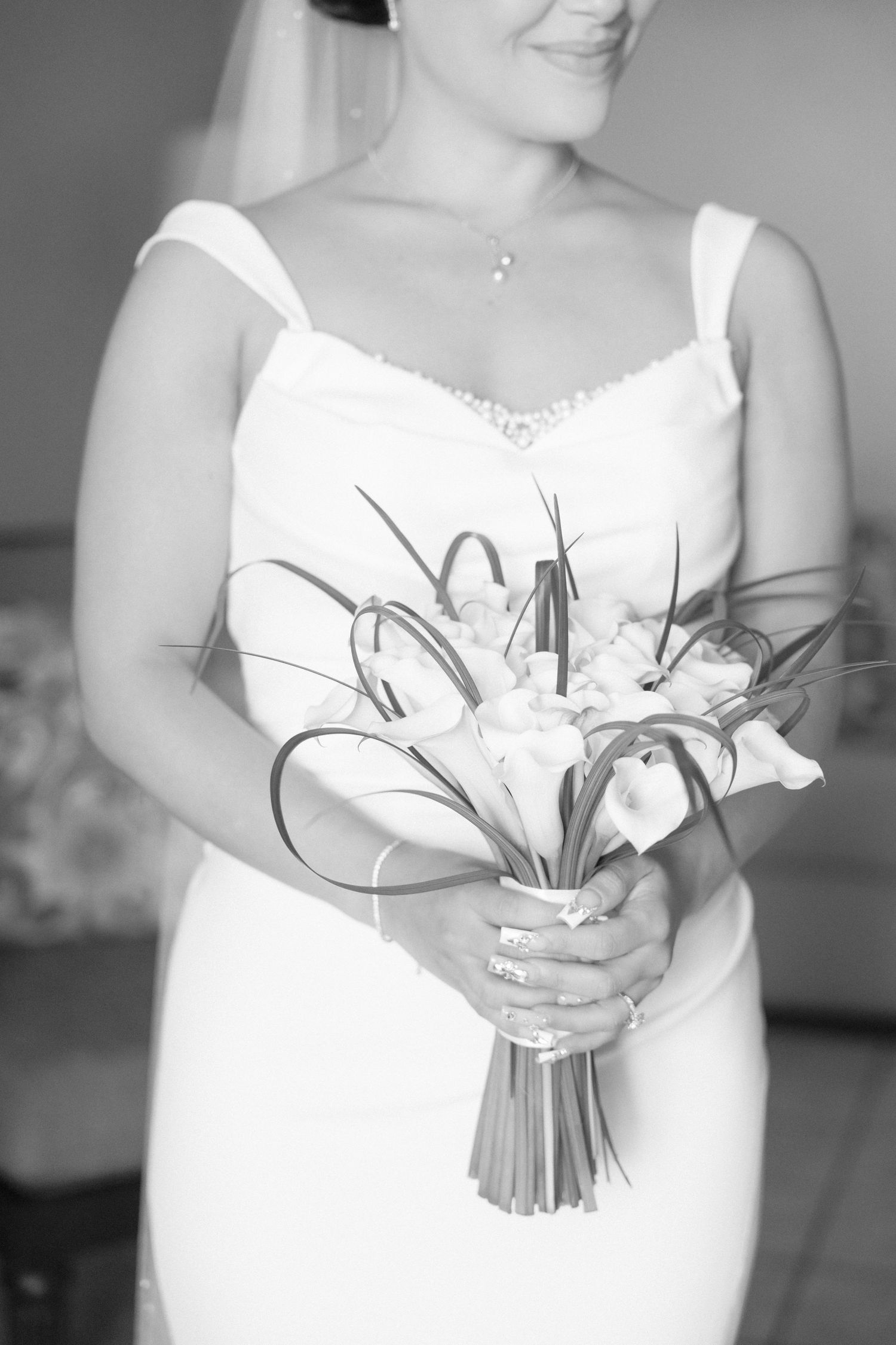 Close-up of white lily bouquet being held in white wedding dress.