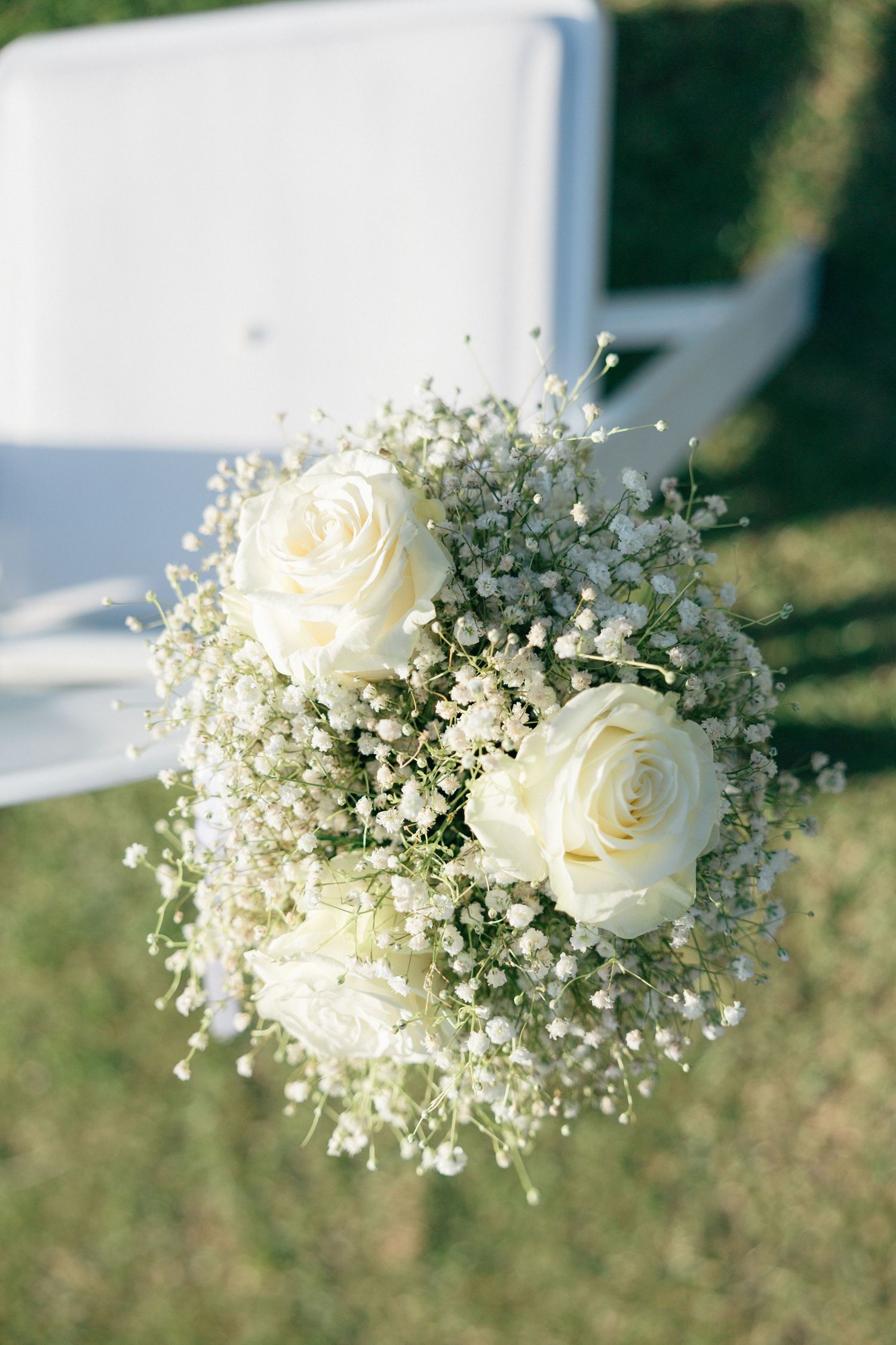 A delicate white rose and baby's breath bridal bouquet captured in natural sunlight.