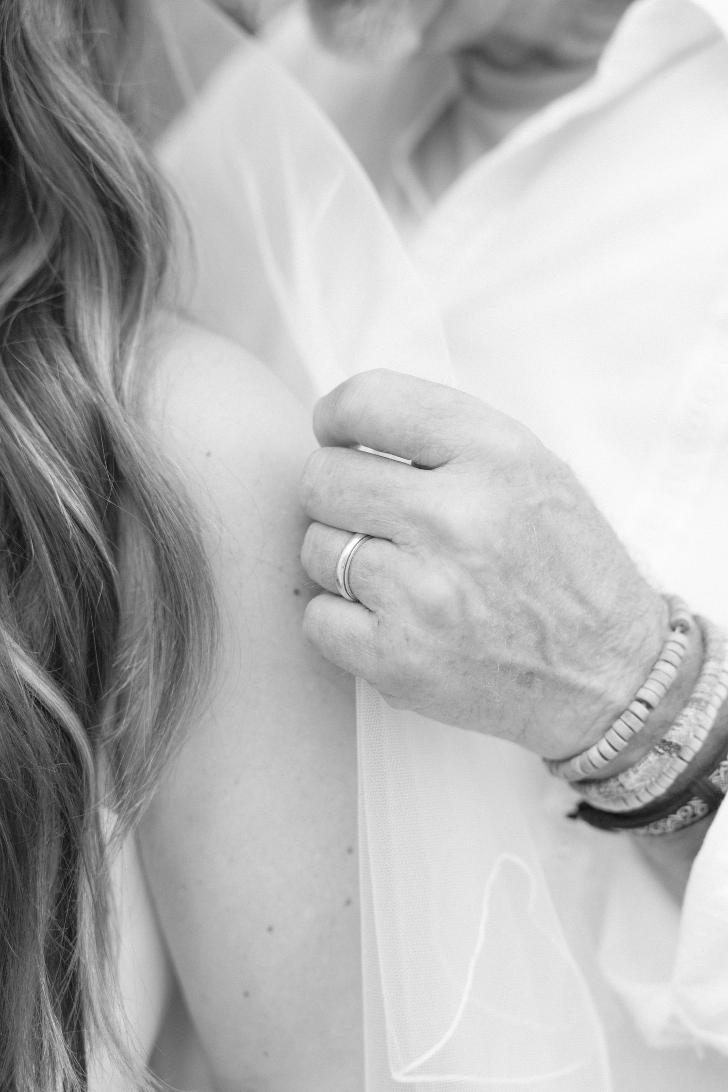 Close-up detail of wedding rings and bracelets in black and white.