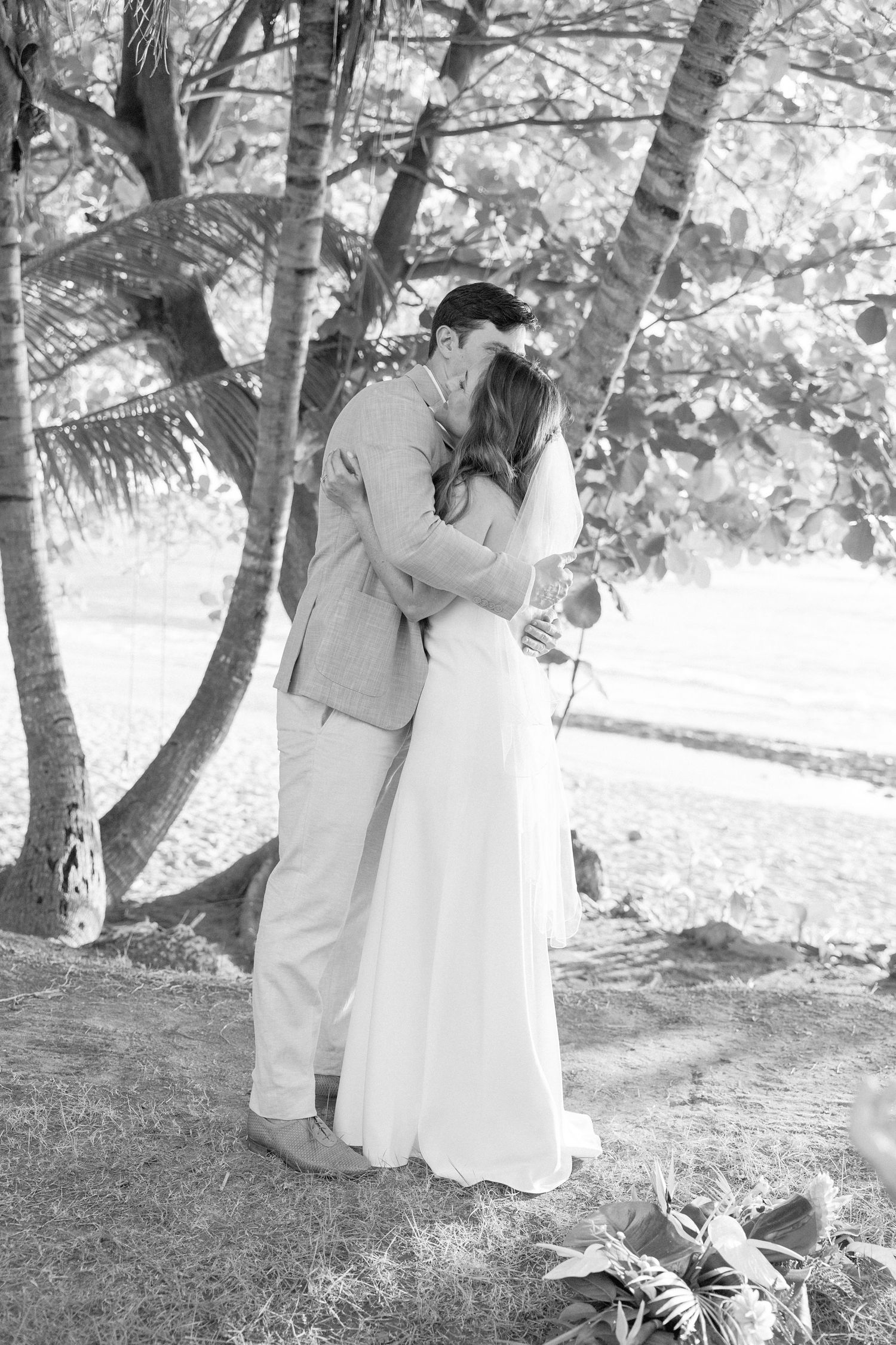 A romantic outdoor wedding photoshoot in black and white with a couple among trees.