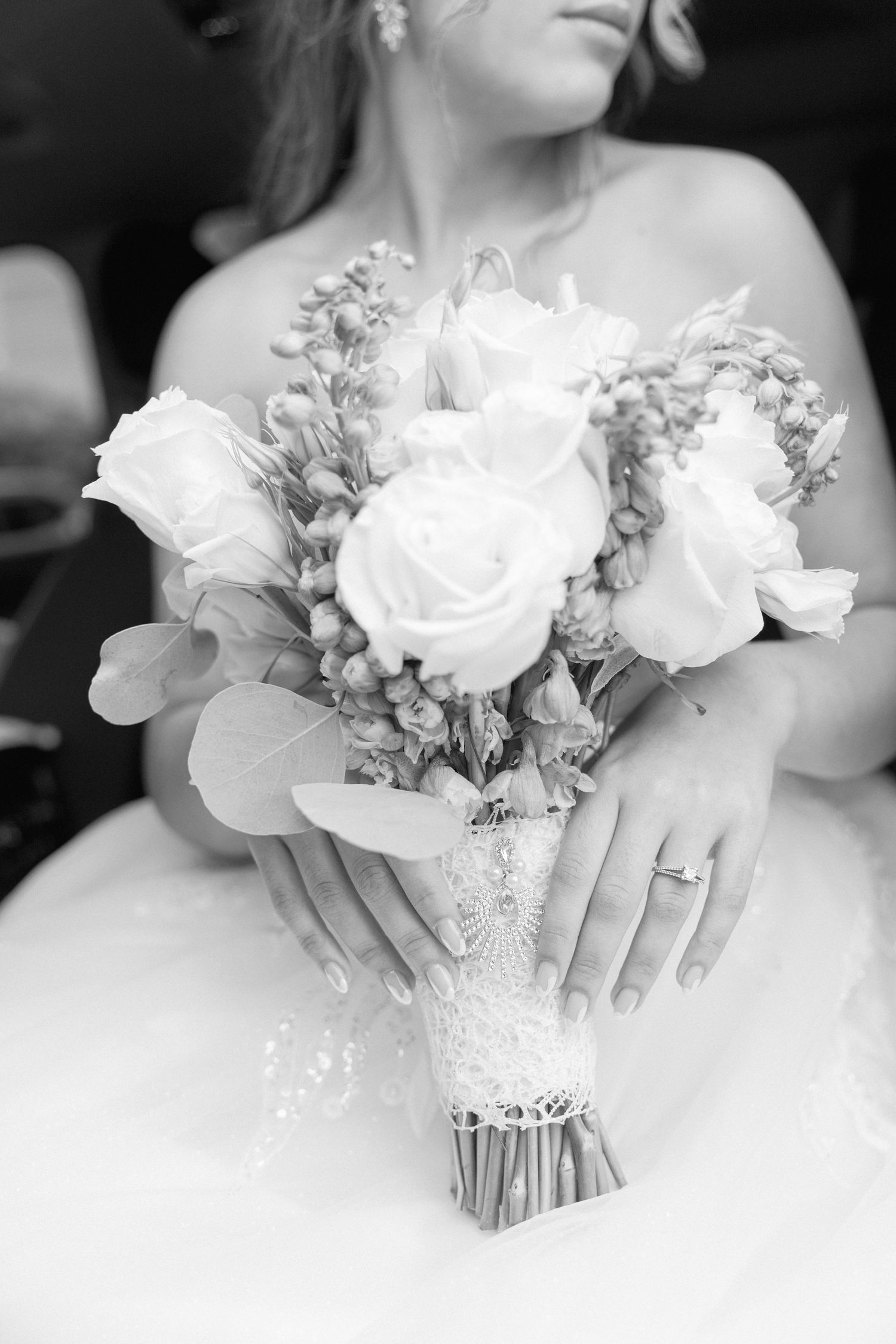 Elegant white bridal bouquet with roses and delicate flowers against a wedding dress.