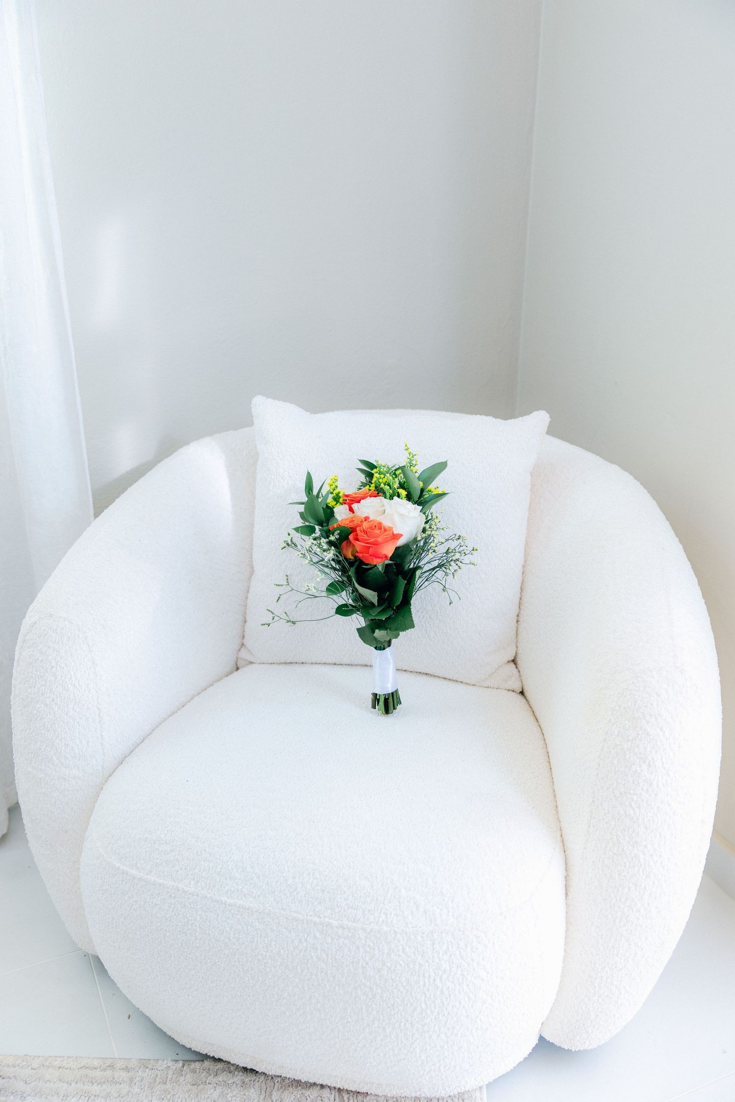 White cushioned seating area decorated with coral and white floral arrangements.