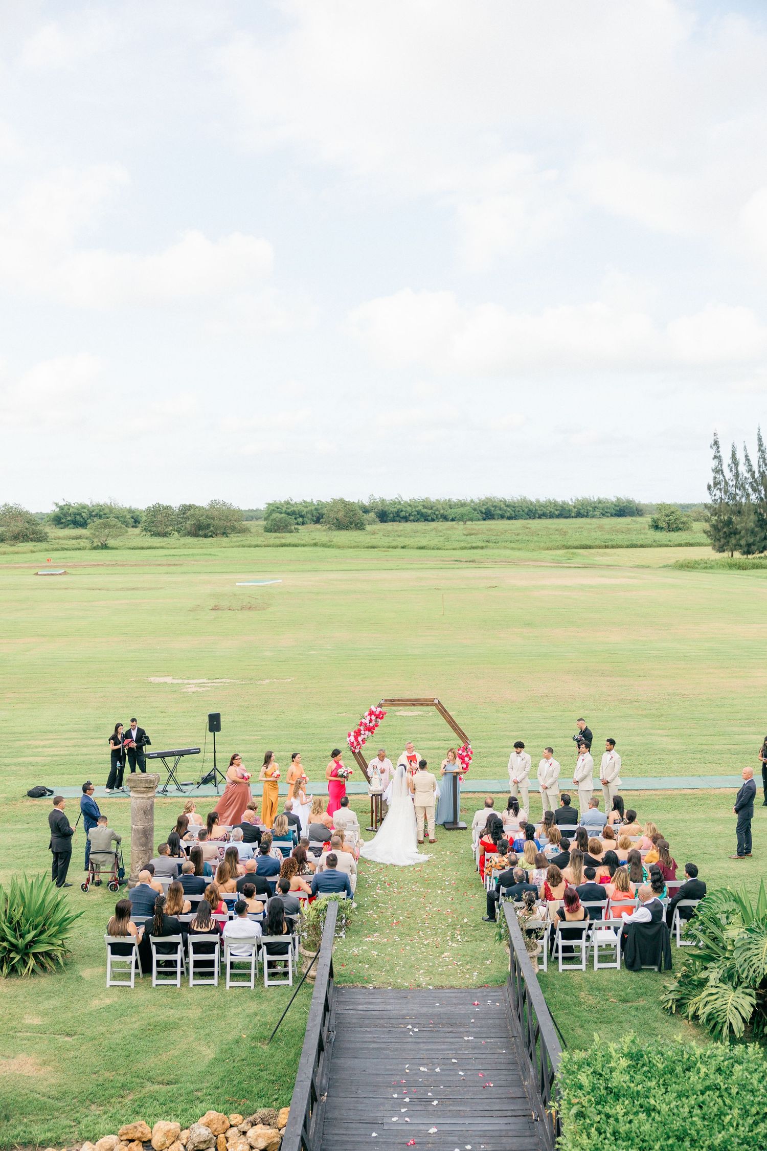 Outdoor wedding ceremony setup with white chairs and natural landscape backdrop.