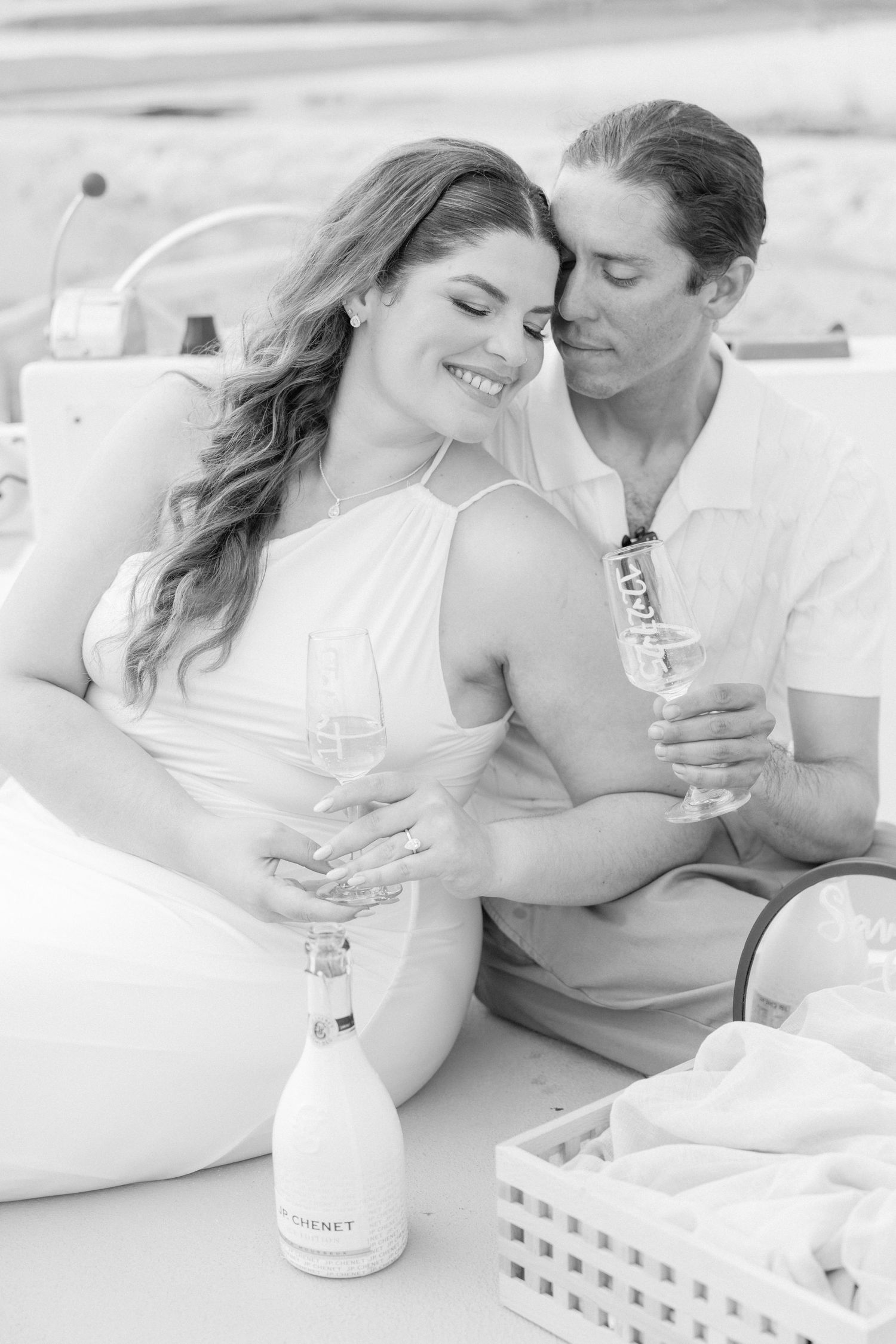 A couple enjoys wine together while relaxing on white cushions.