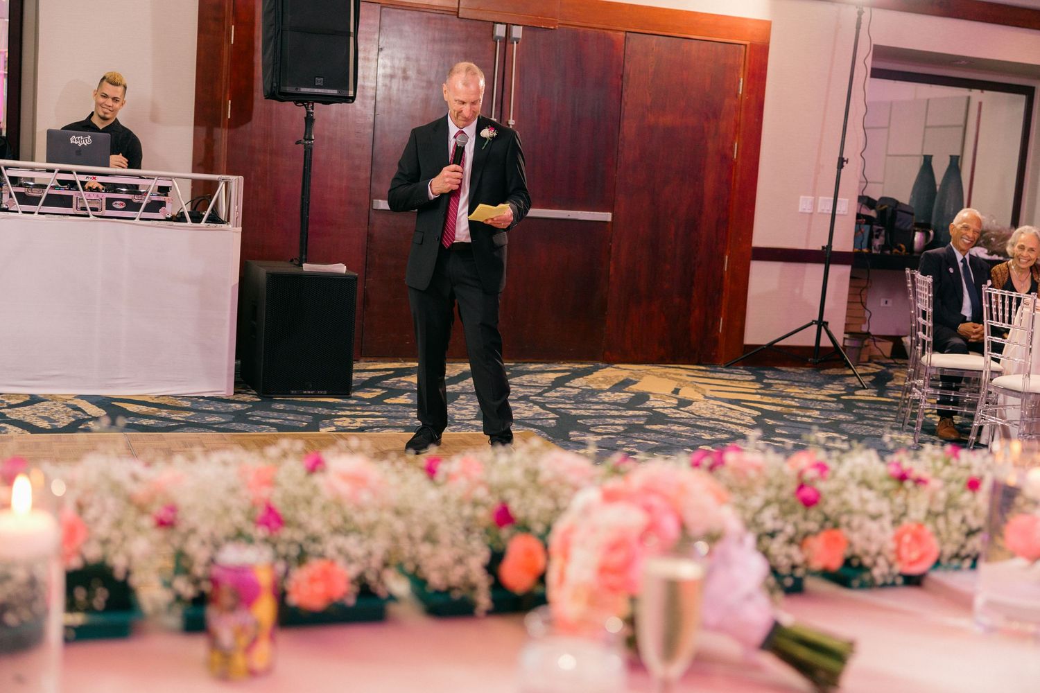 Elegant wedding reception venue decorated with pink floral arrangements and soft lighting.