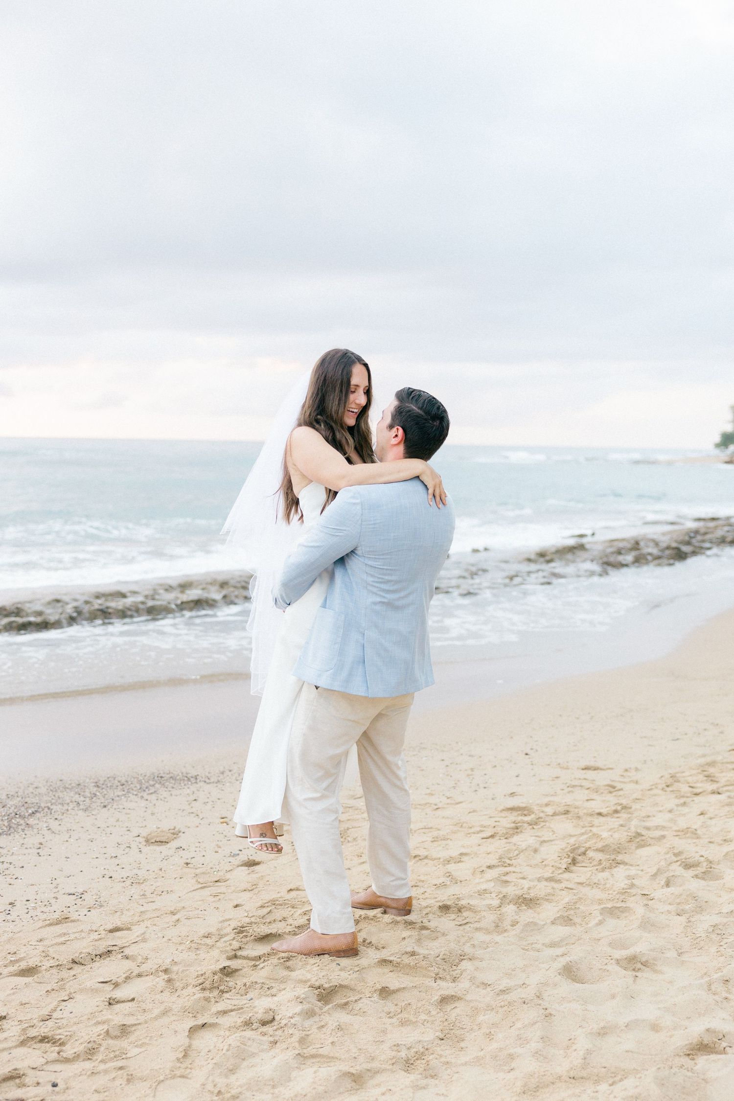 Romantic beach moment with couple embracing on sandy shore at sunset.