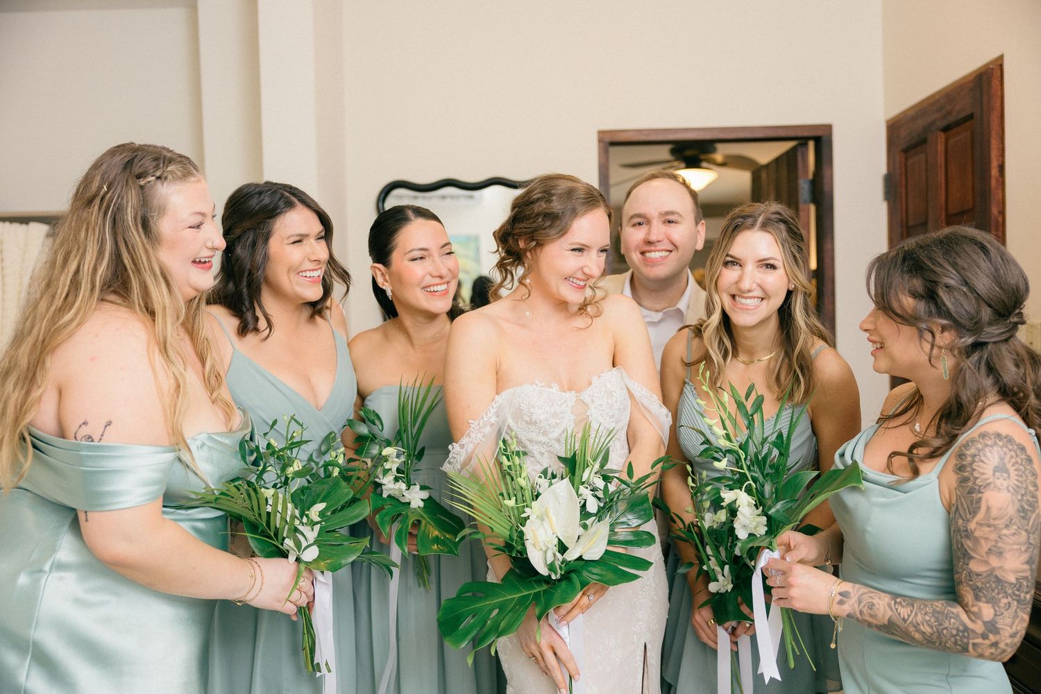 Wedding party shares candid laughter while gathered together in their mint green attire.