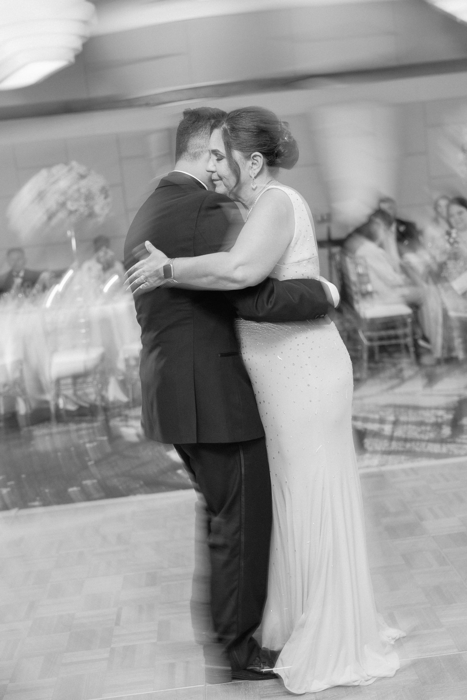 Black and white photo of a couple embracing during their wedding dance.