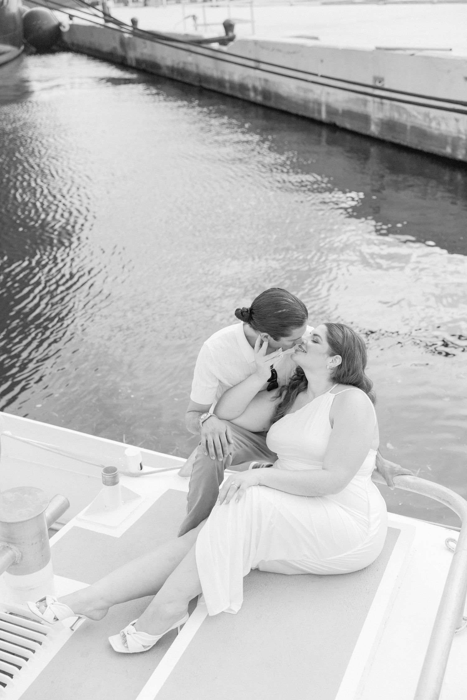 Black and white photo of couple sharing tender moments on a boat.