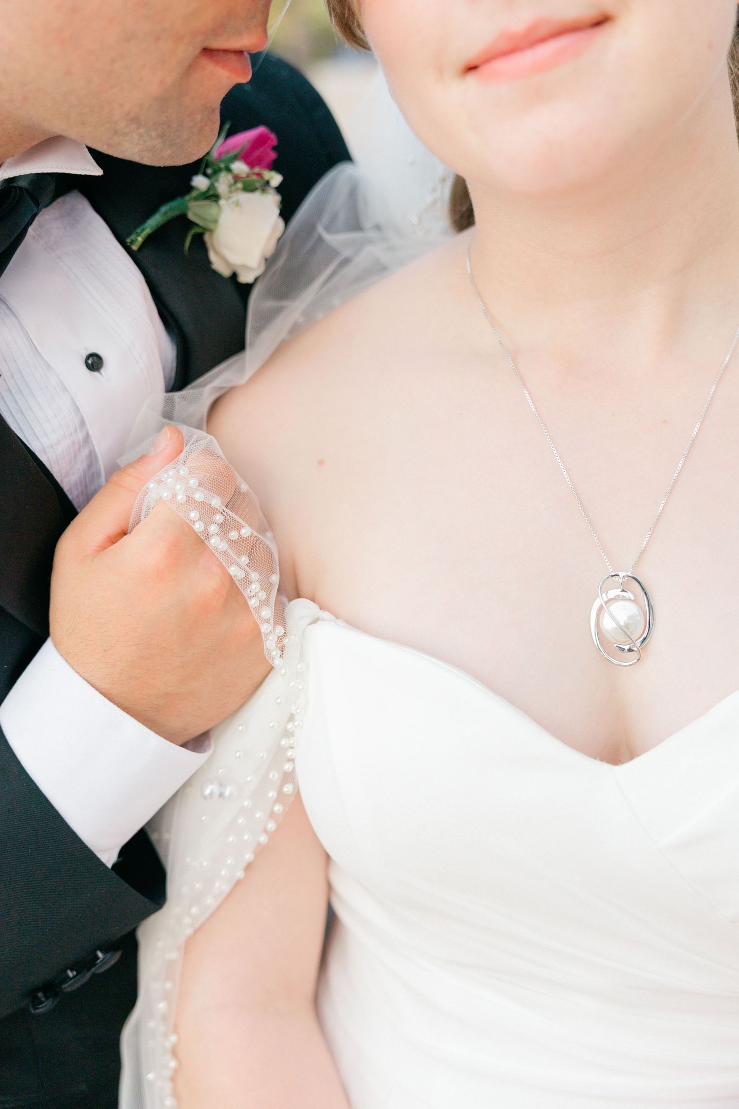 Close-up details of bridal jewelry and lace against white wedding dress.