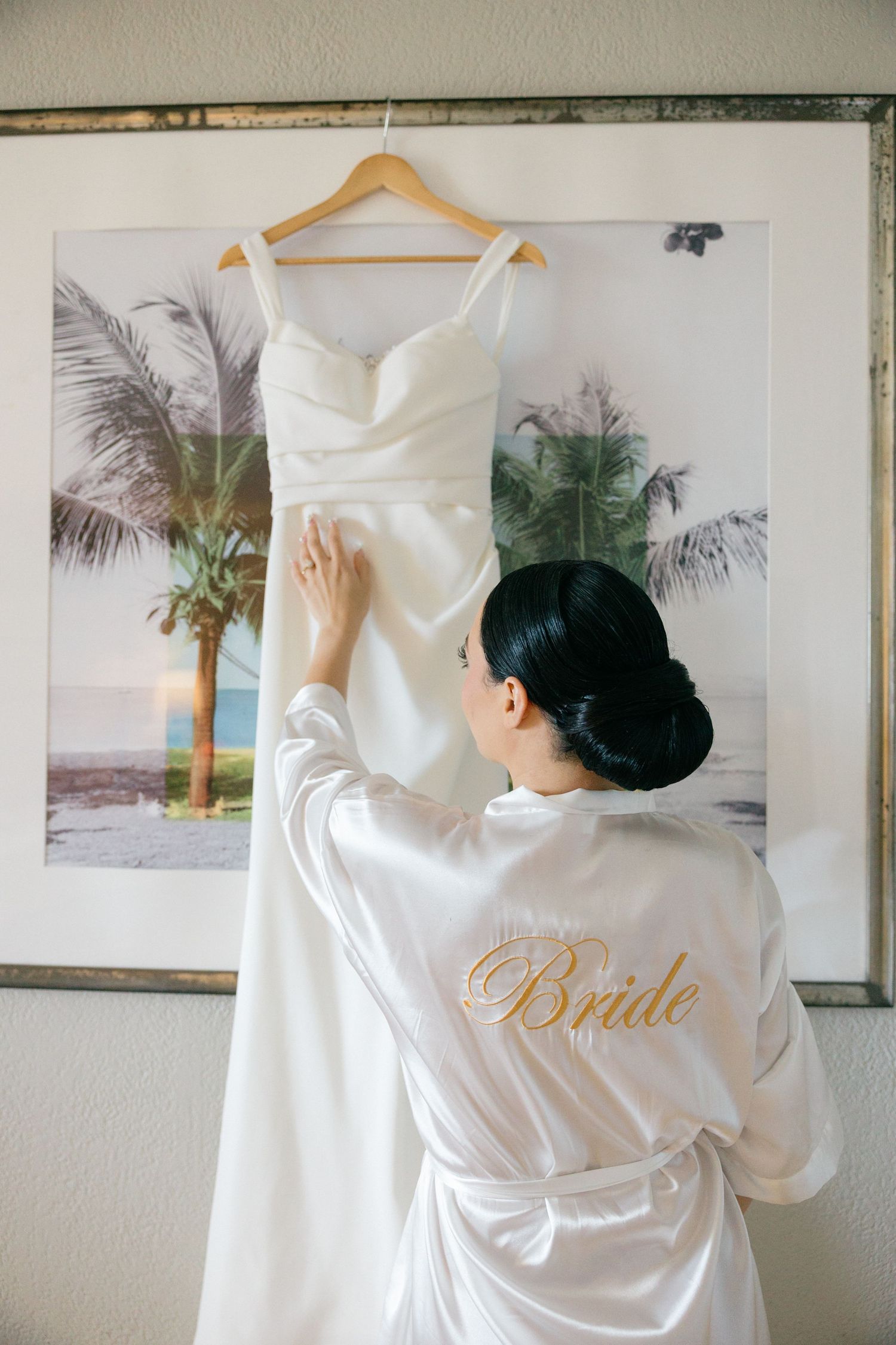 White bridal robe with gold lettering displayed against tropical artwork.
