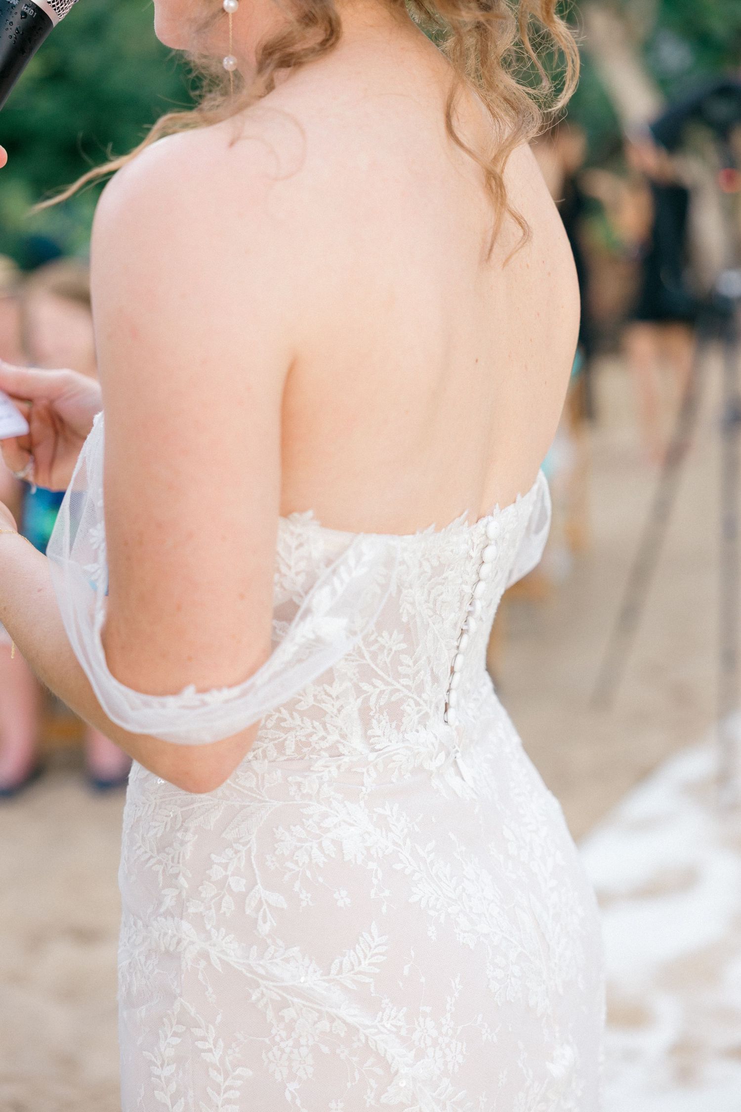 Close-up detail of delicate lace wedding dress back with buttons.