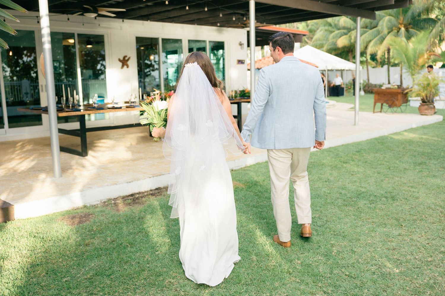 Outdoor wedding venue with green lawn and palm trees in tropical setting.
