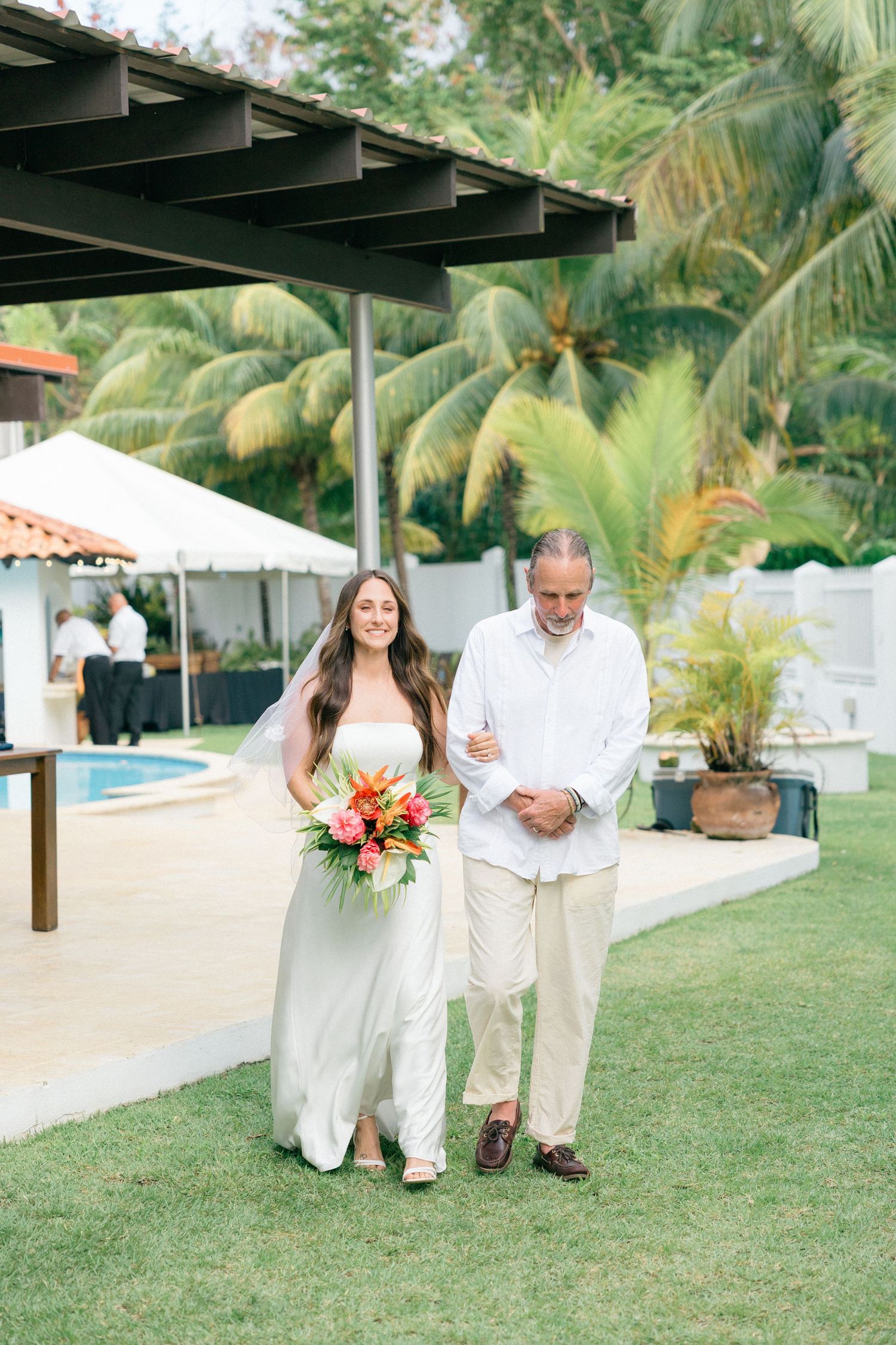 Tropical garden wedding ceremony with palm trees and white decor.