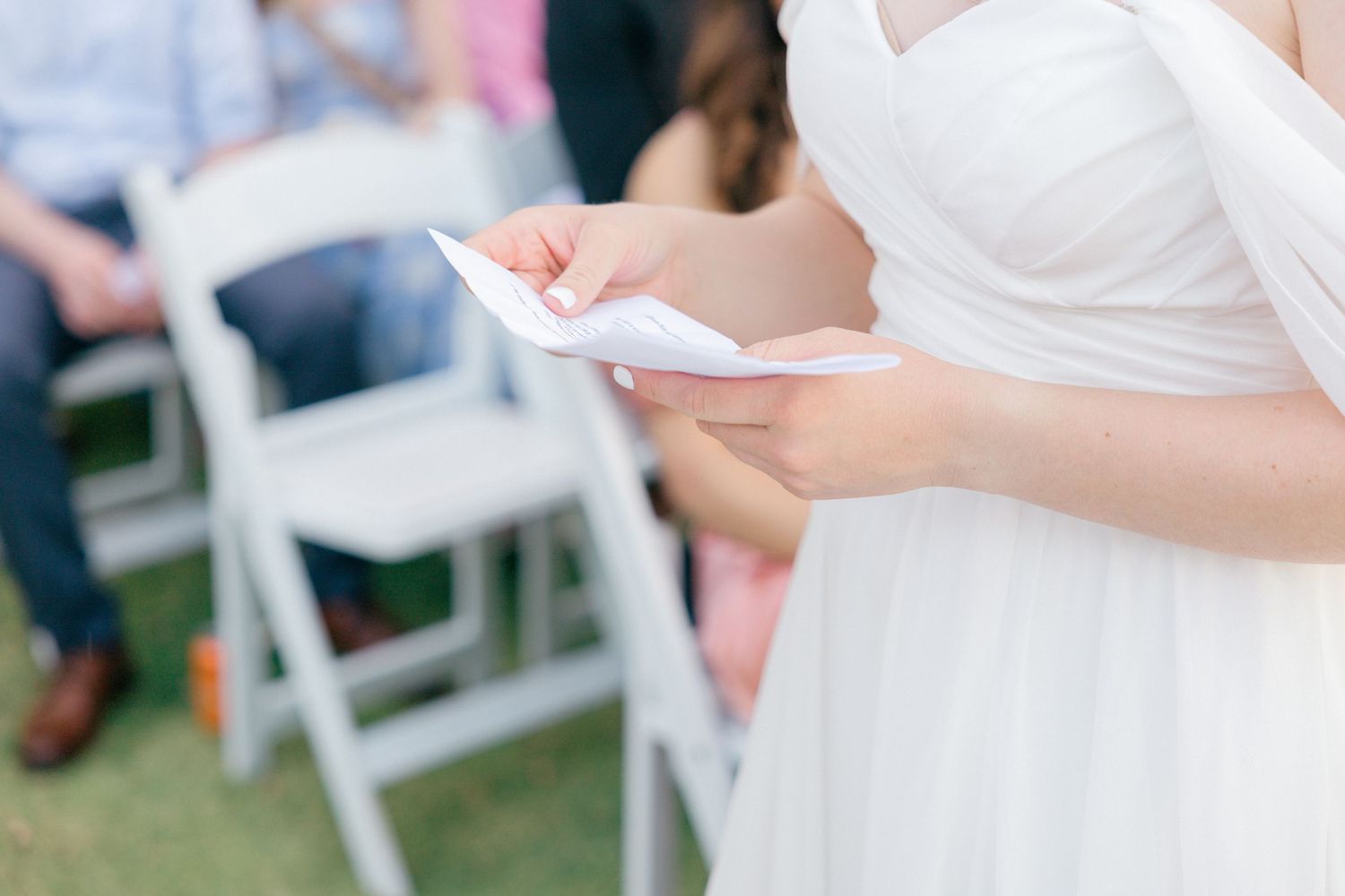 Close-up view of a flowing white wedding dress during an outdoor ceremony.