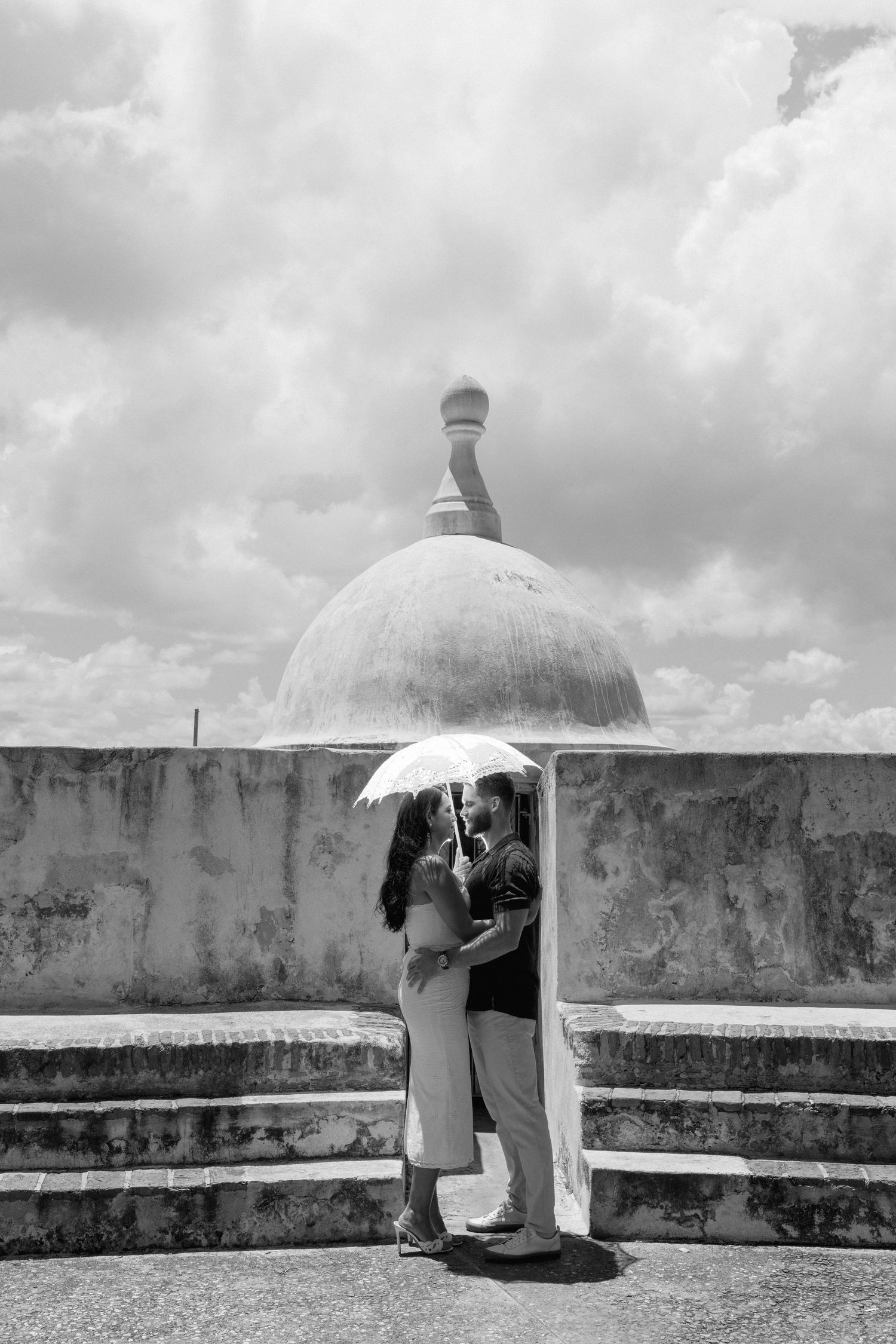 Black and white series of a couple under an umbrella at a historic stone fortress.