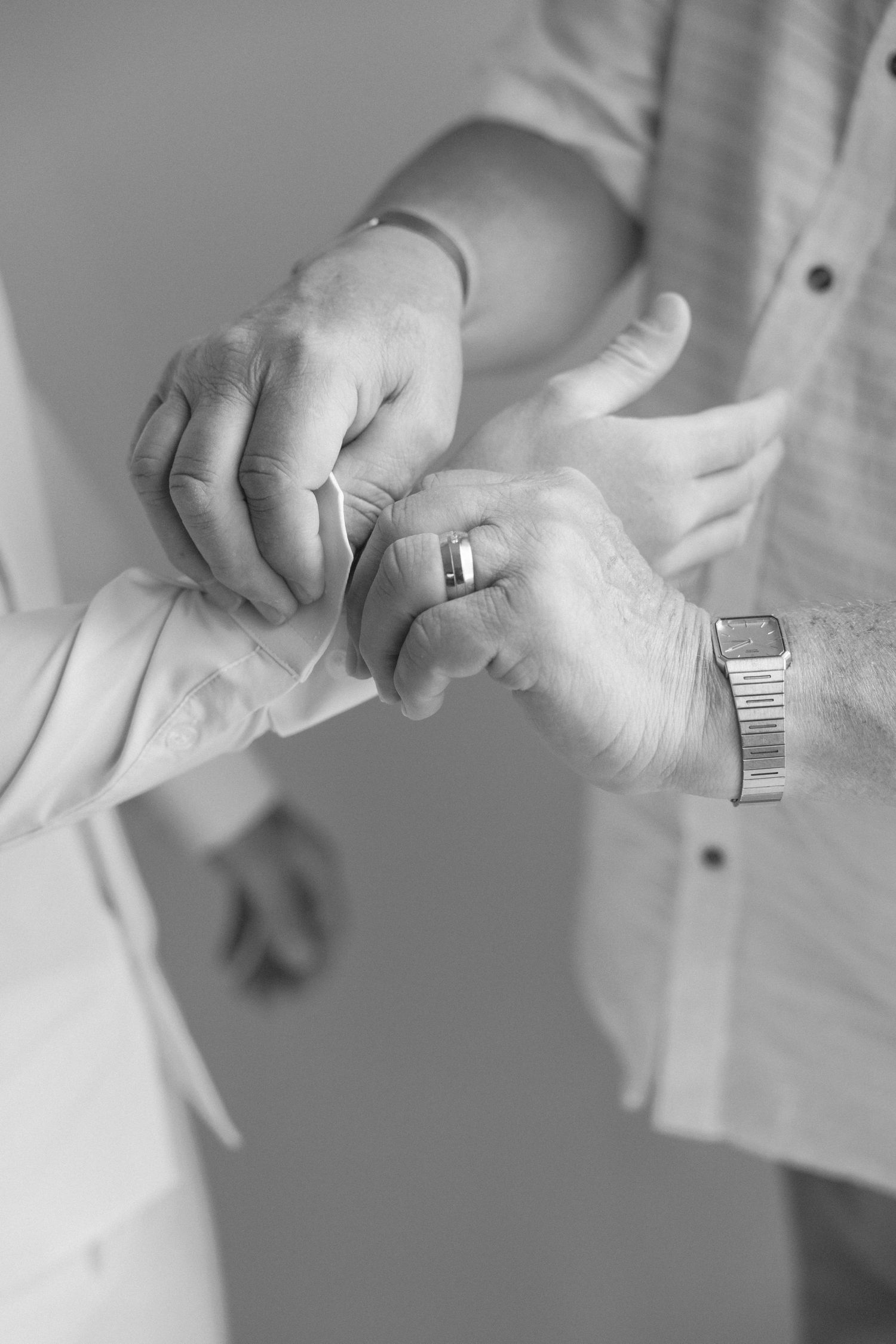 Black and white detail shot of hands adjusting shirt cuffs.