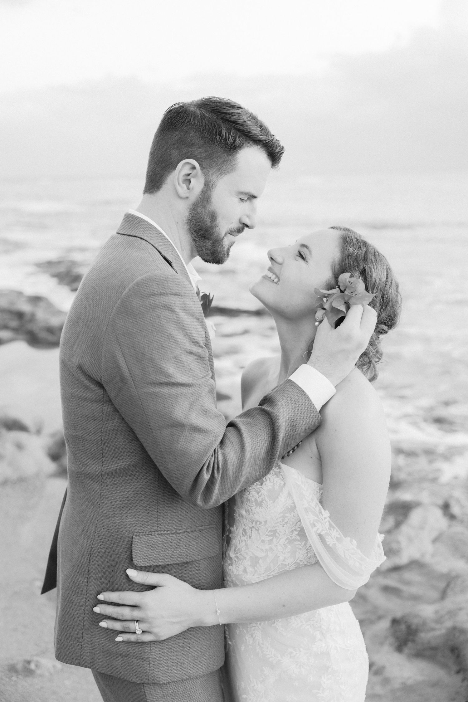 Intimate black and white beach portraits capturing tender moments between newlyweds.