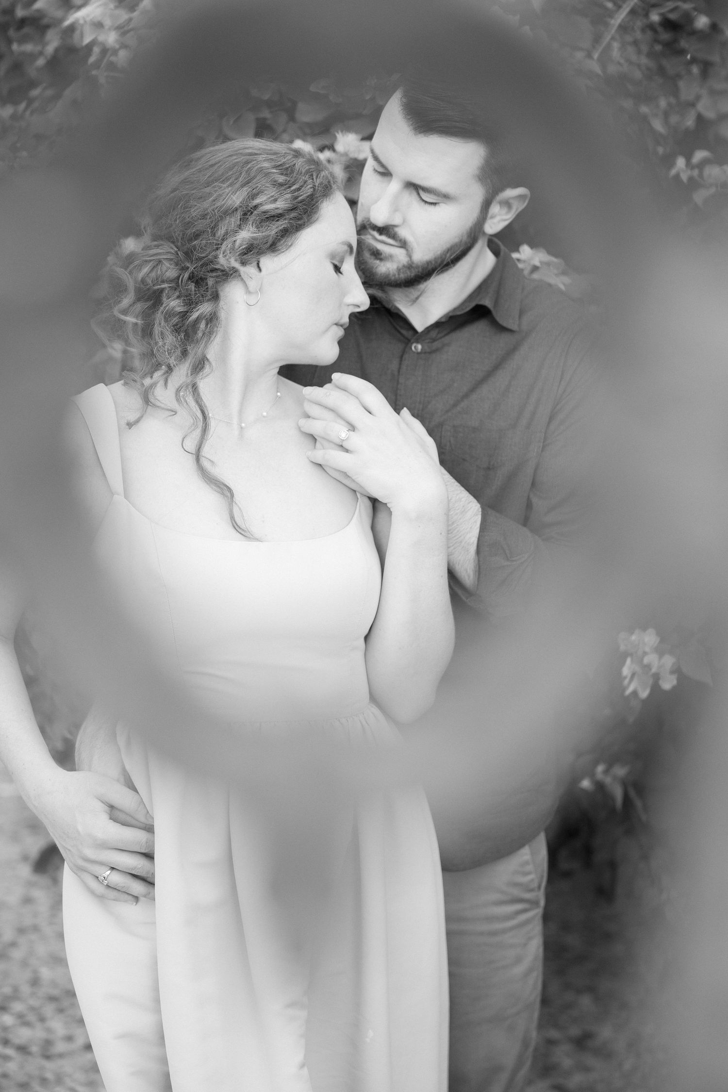 Intimate black and white portrait of a couple sharing a tender moment outdoors.