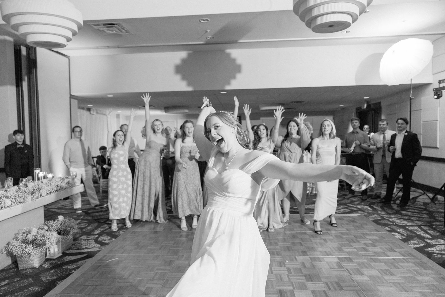 Black and white panoramic view of a wedding reception dance floor with guests celebrating.