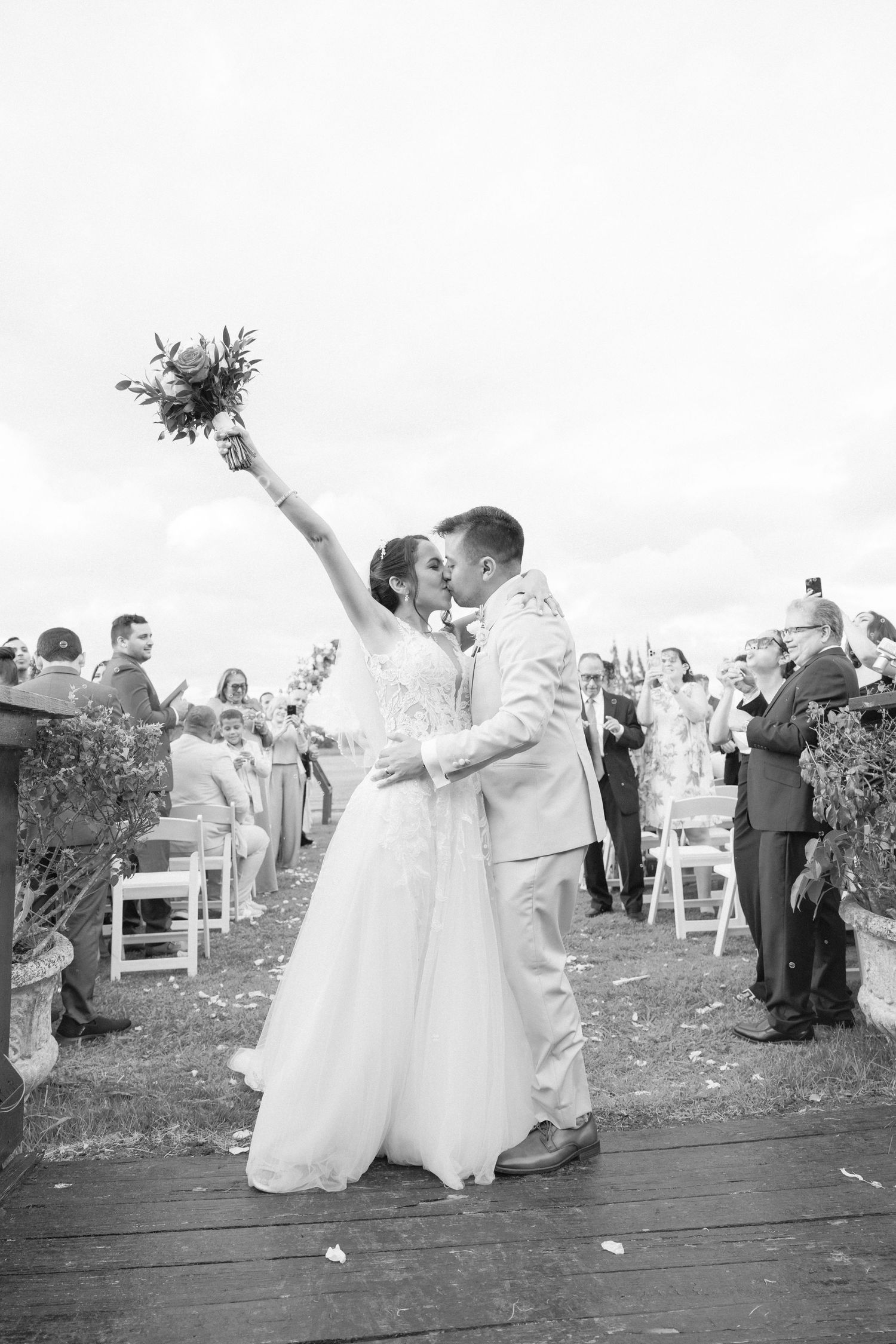 Black and white photo of wedding party celebrating on an outdoor deck.