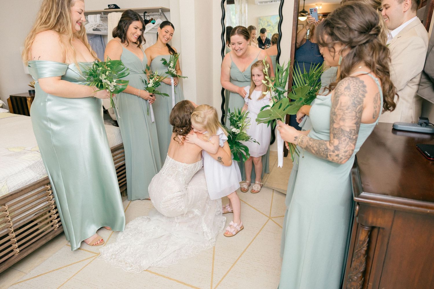 Sweet moment with a young flower girl among the bridal party in seafoam green dresses.