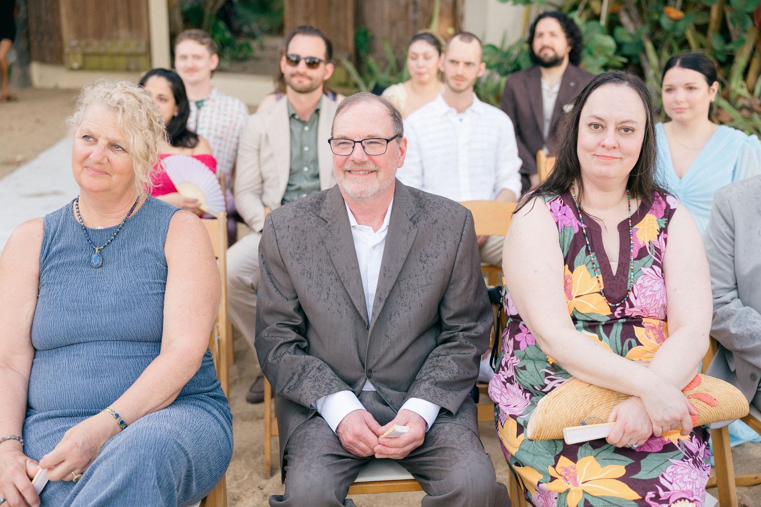 Wedding guests seated outdoors enjoying the ceremony in casual attire.