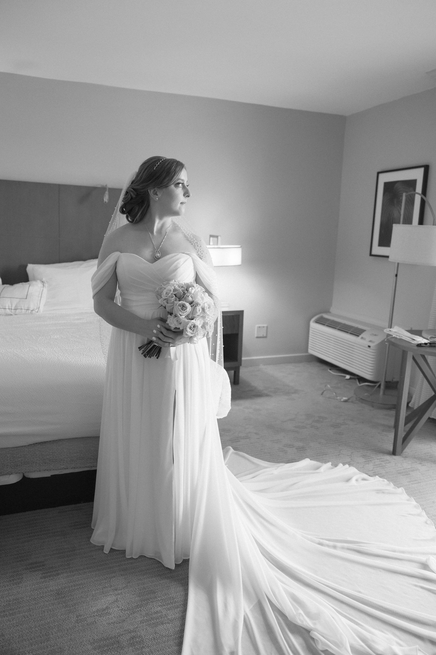 Full-length view of flowing wedding dress train in hotel room.