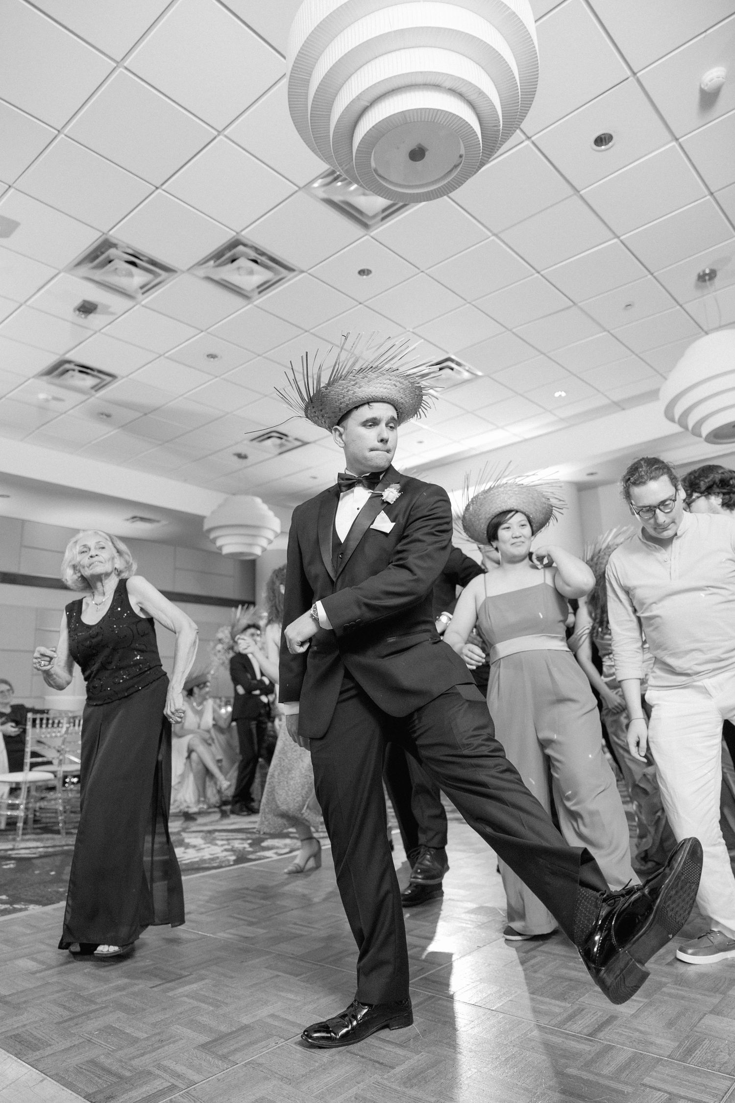 Black and white shots of guests performing synchronized dance moves at wedding reception.