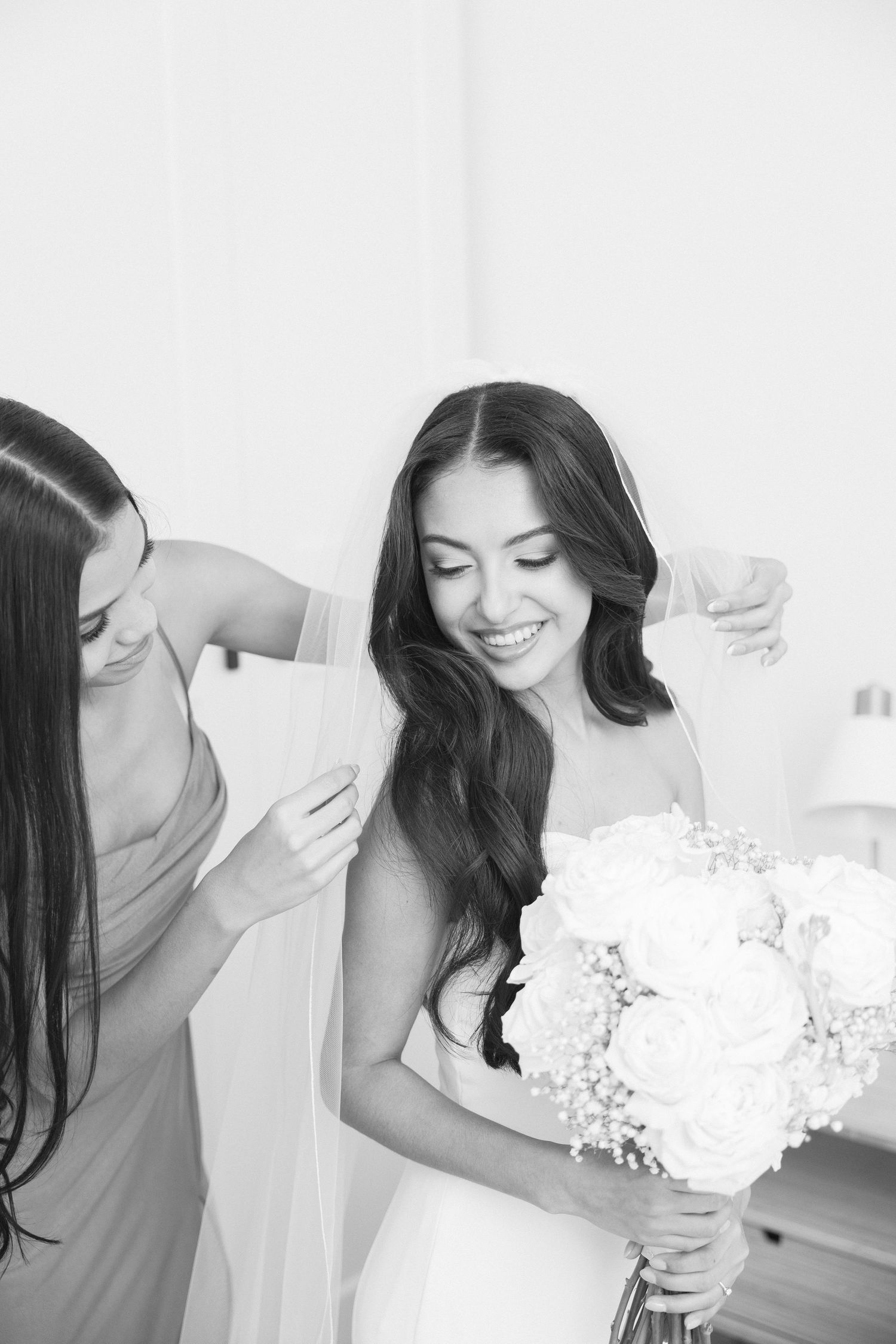 Bride holding a white floral bouquet while getting ready for her wedding day.