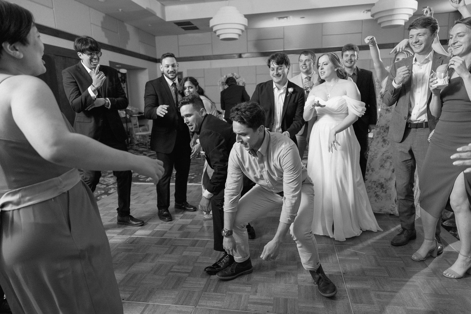 Wedding party members performing a group dance routine at an indoor reception.