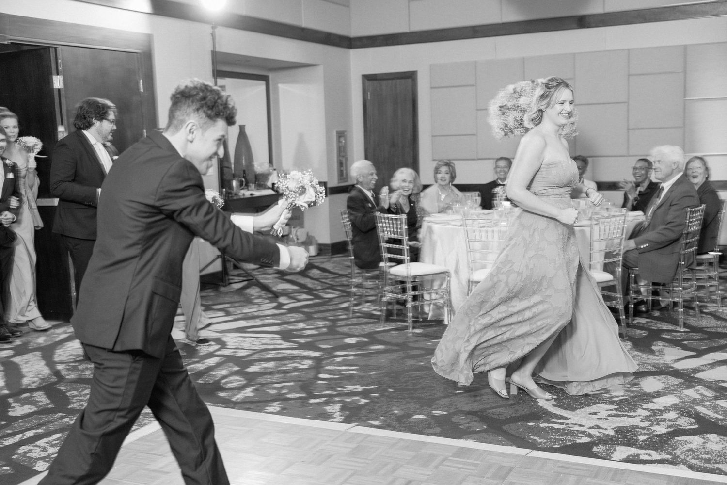 Black and white photo of couple dancing energetically at wedding reception.