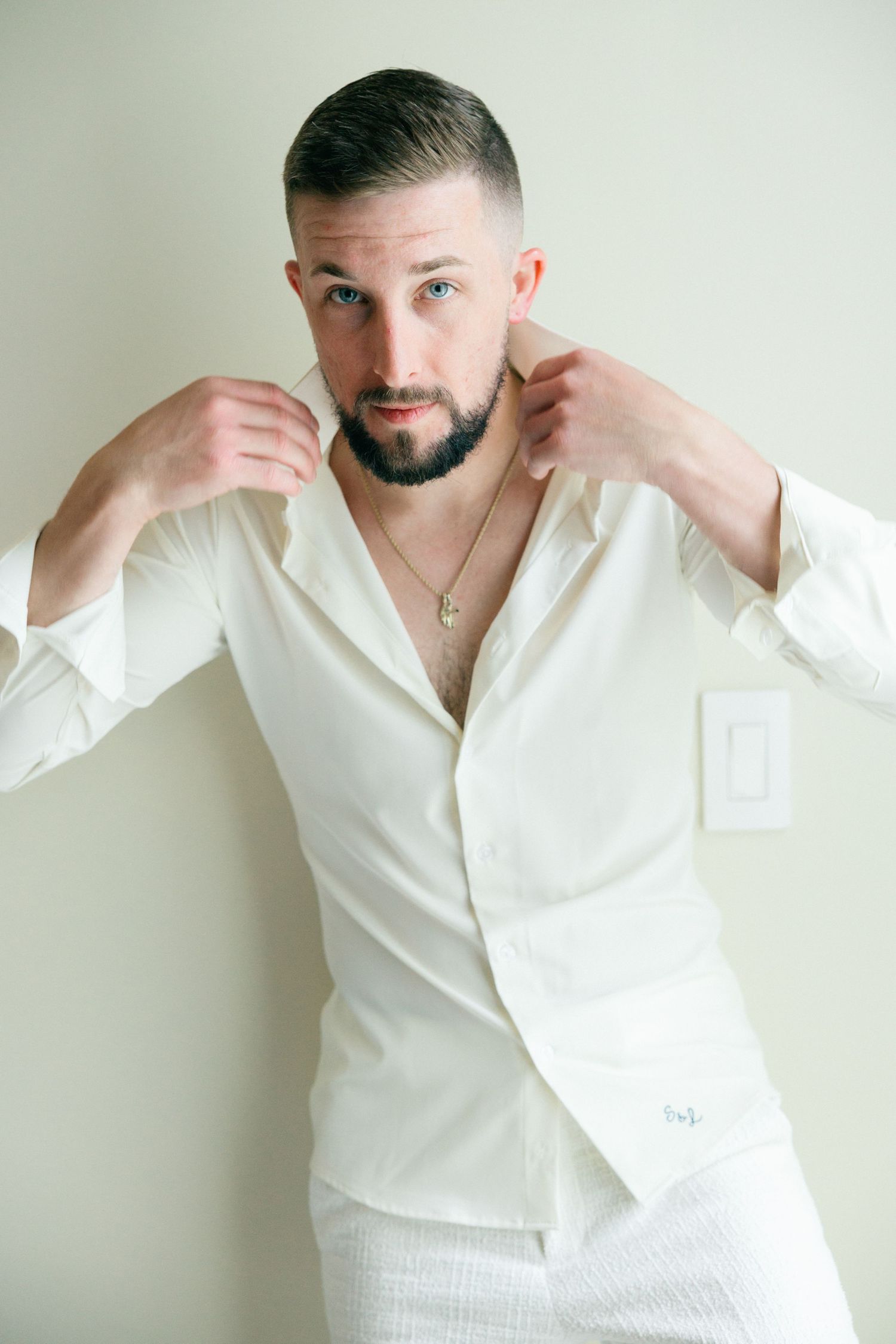 Fashion portrait showing all-white ensemble with open collar shirt.