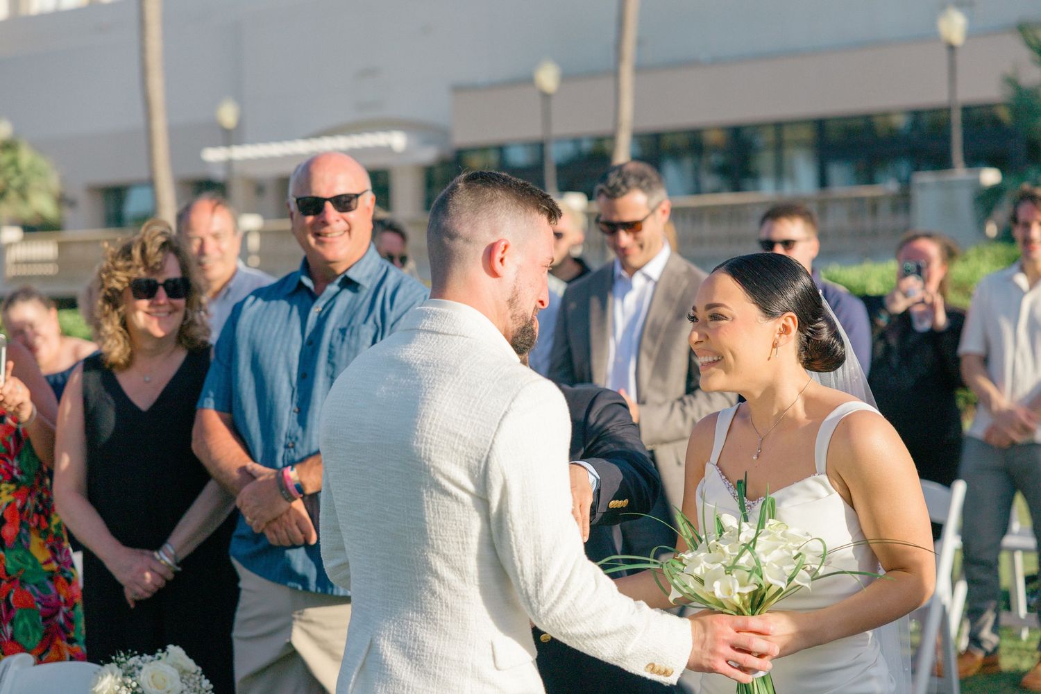 Wedding celebration on a sunny day with guests mingling on a grassy lawn.