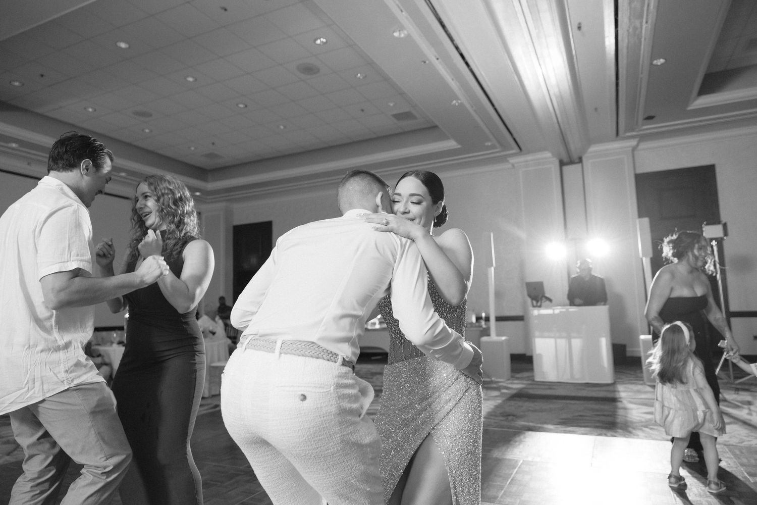 Couples dancing and celebrating at a lively indoor wedding reception party.